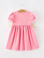 Young girl wearing Rylee Faith Designs embroidered back to school dress with bow puff sleeves.
