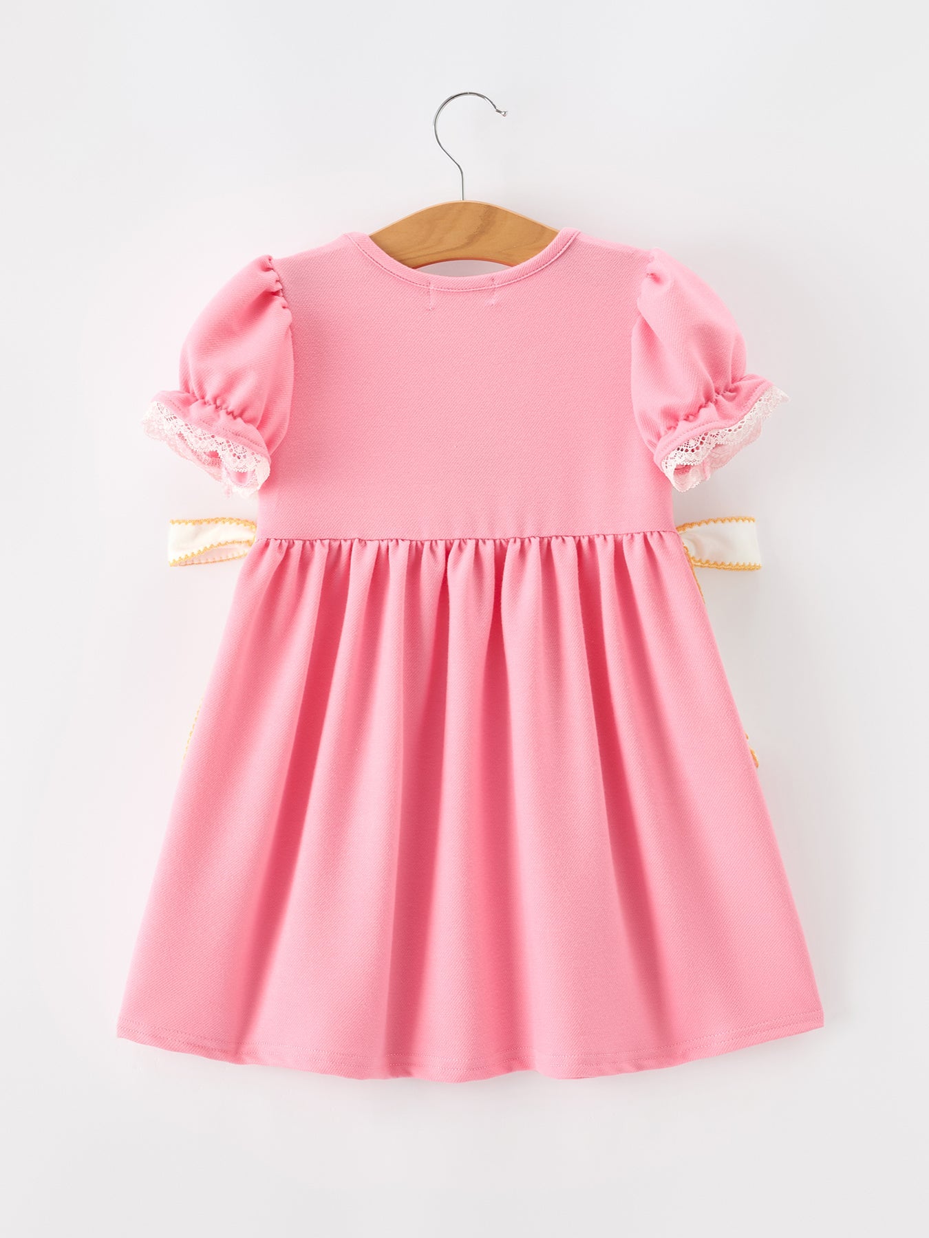 Young girl wearing Rylee Faith Designs embroidered back to school dress with bow puff sleeves.