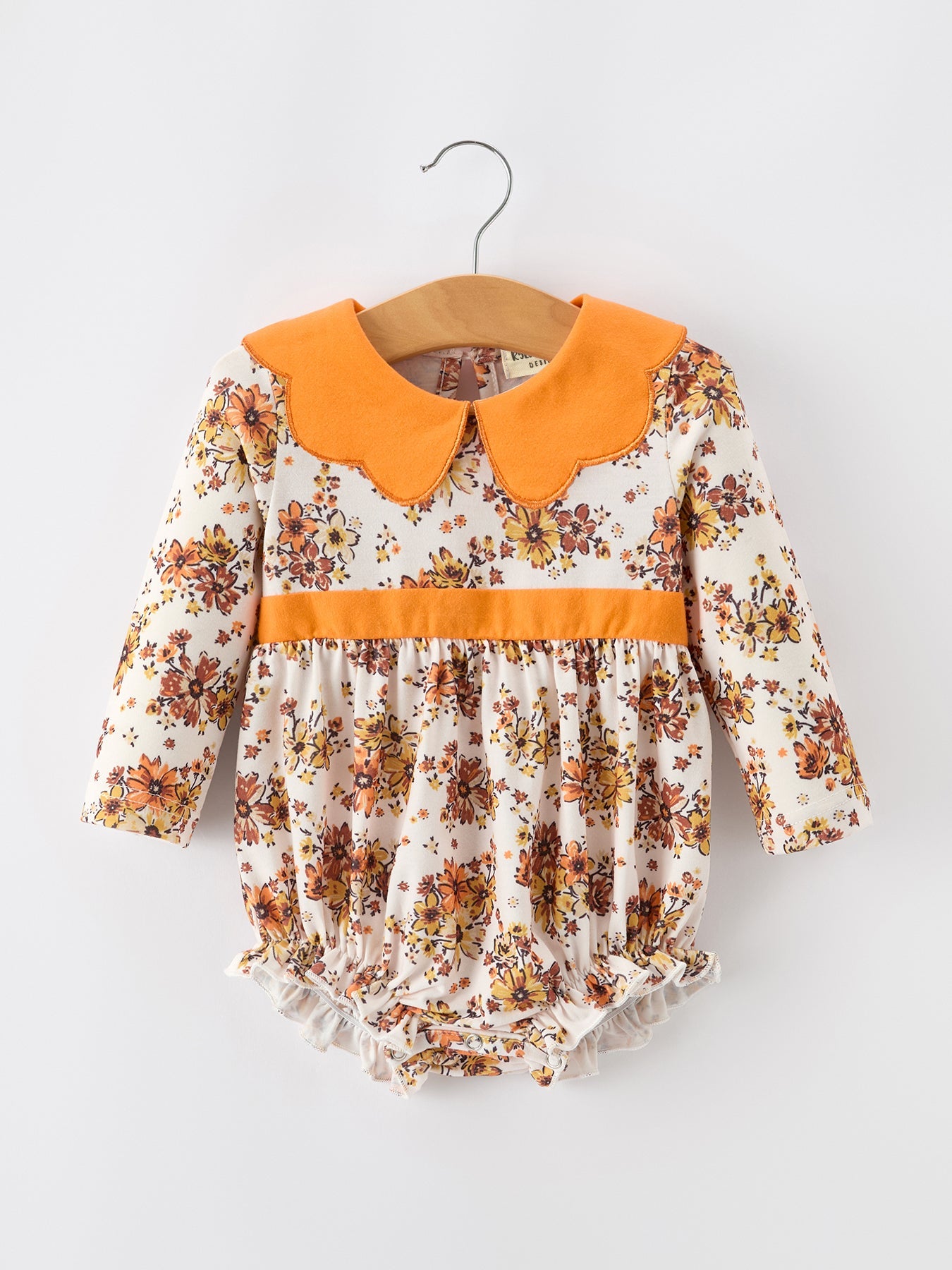 Baby bubble romper in orange floral print with contrast orange petals collar and ruffle leg openings.