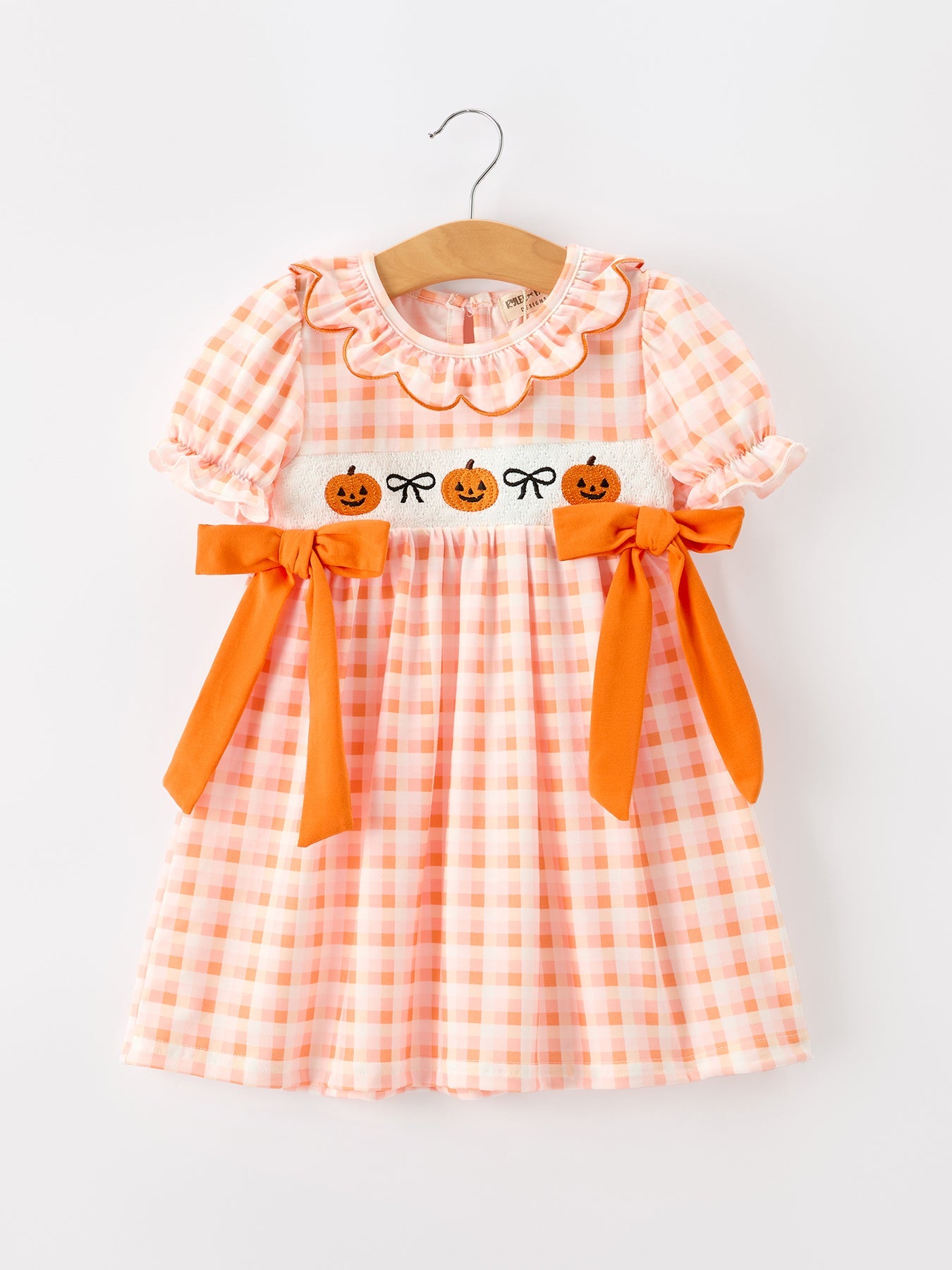 Orange gingham girls dress with embroidered jack-o'-lantern details, puff sleeves, scalloped collar, and side bows.
