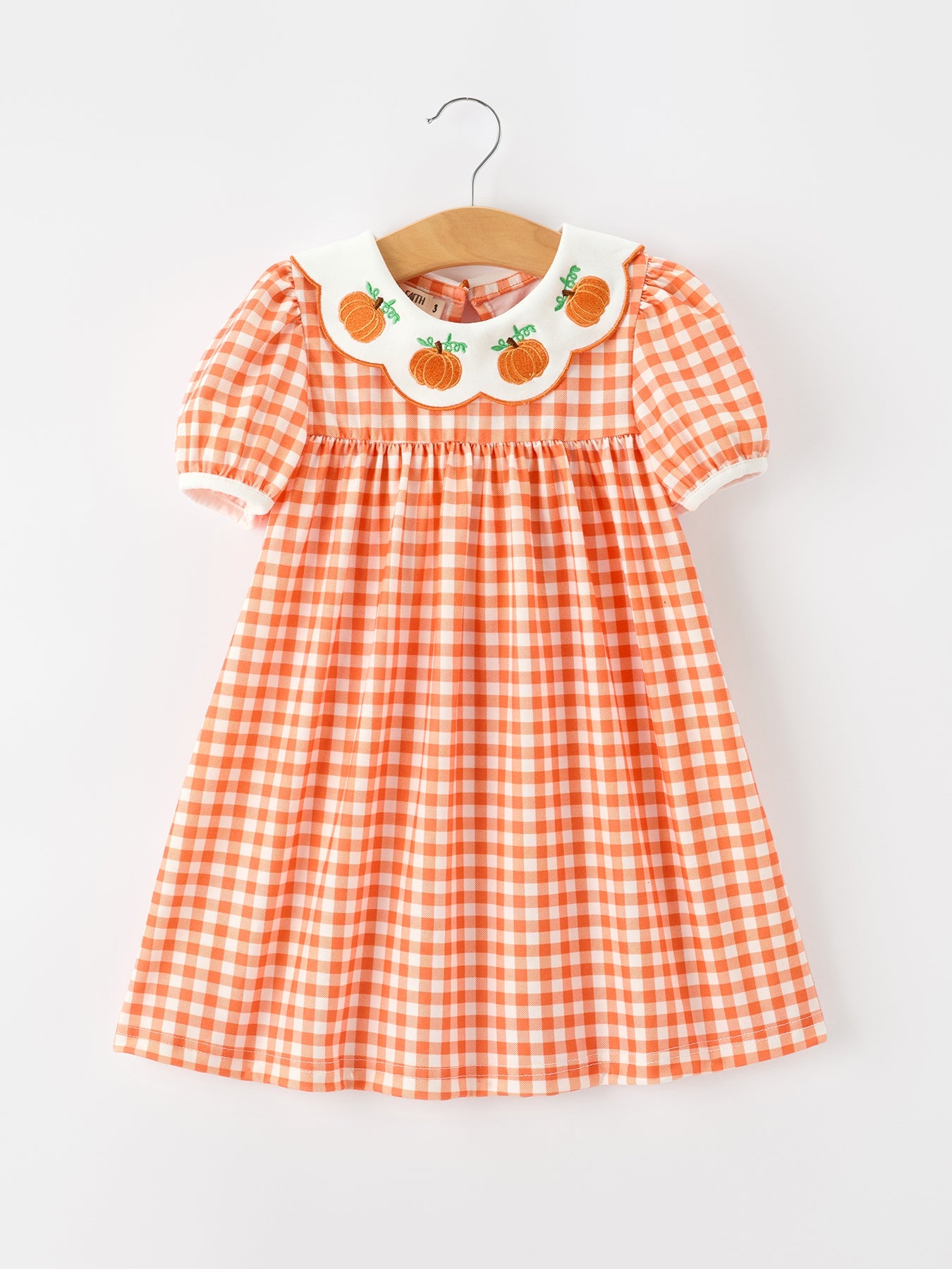 Girls' plaid dress with pumpkin-embroidered fan-shaped neckline and puff sleeves.