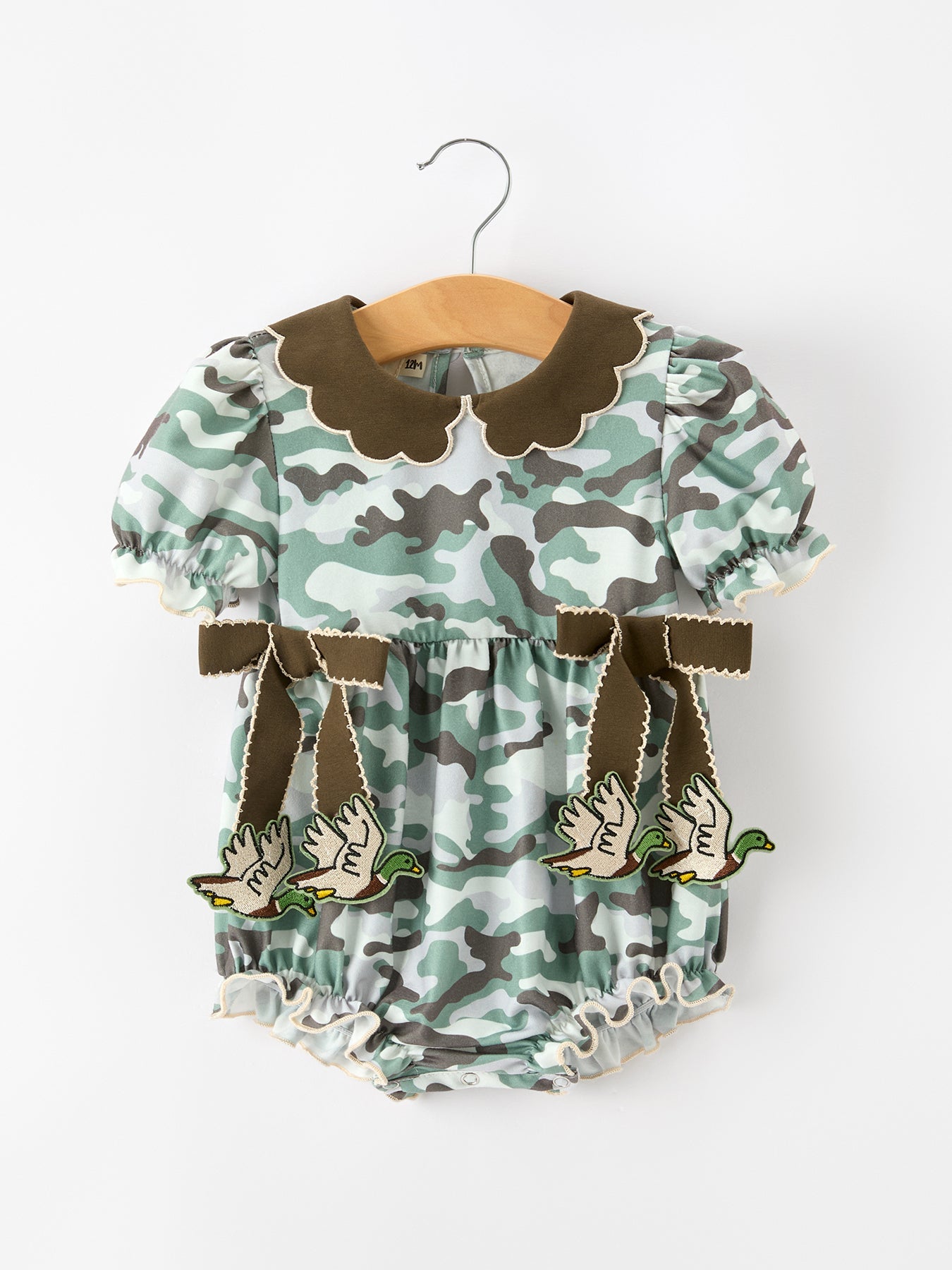 Girls ruffle bubble romper in fall camouflage print with bow accents, puff sleeves, and layered ruffle details.