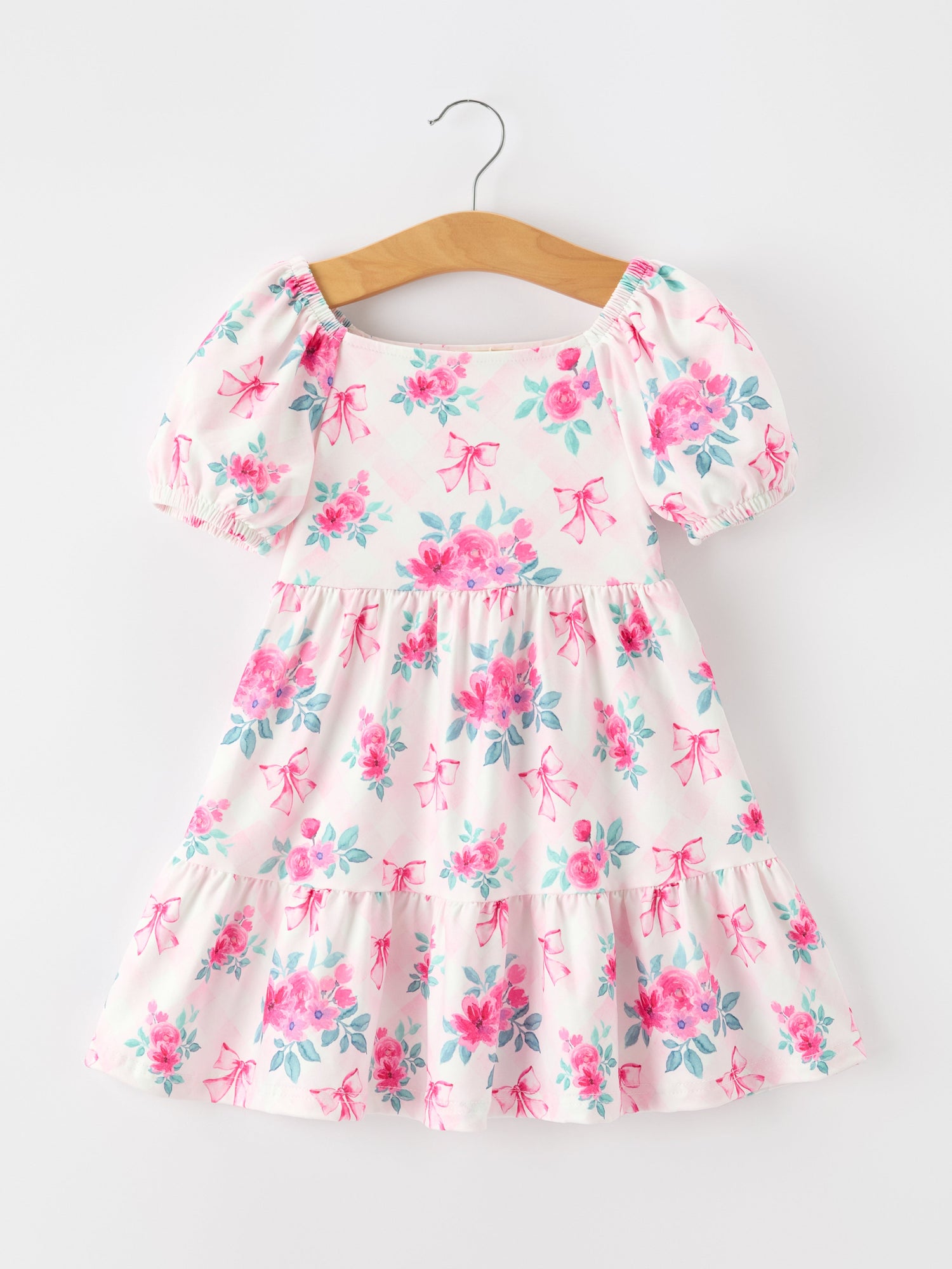 Pink floral girls dress with puff sleeves, bow accents, square neckline, gathered waist, and ruffle hem.