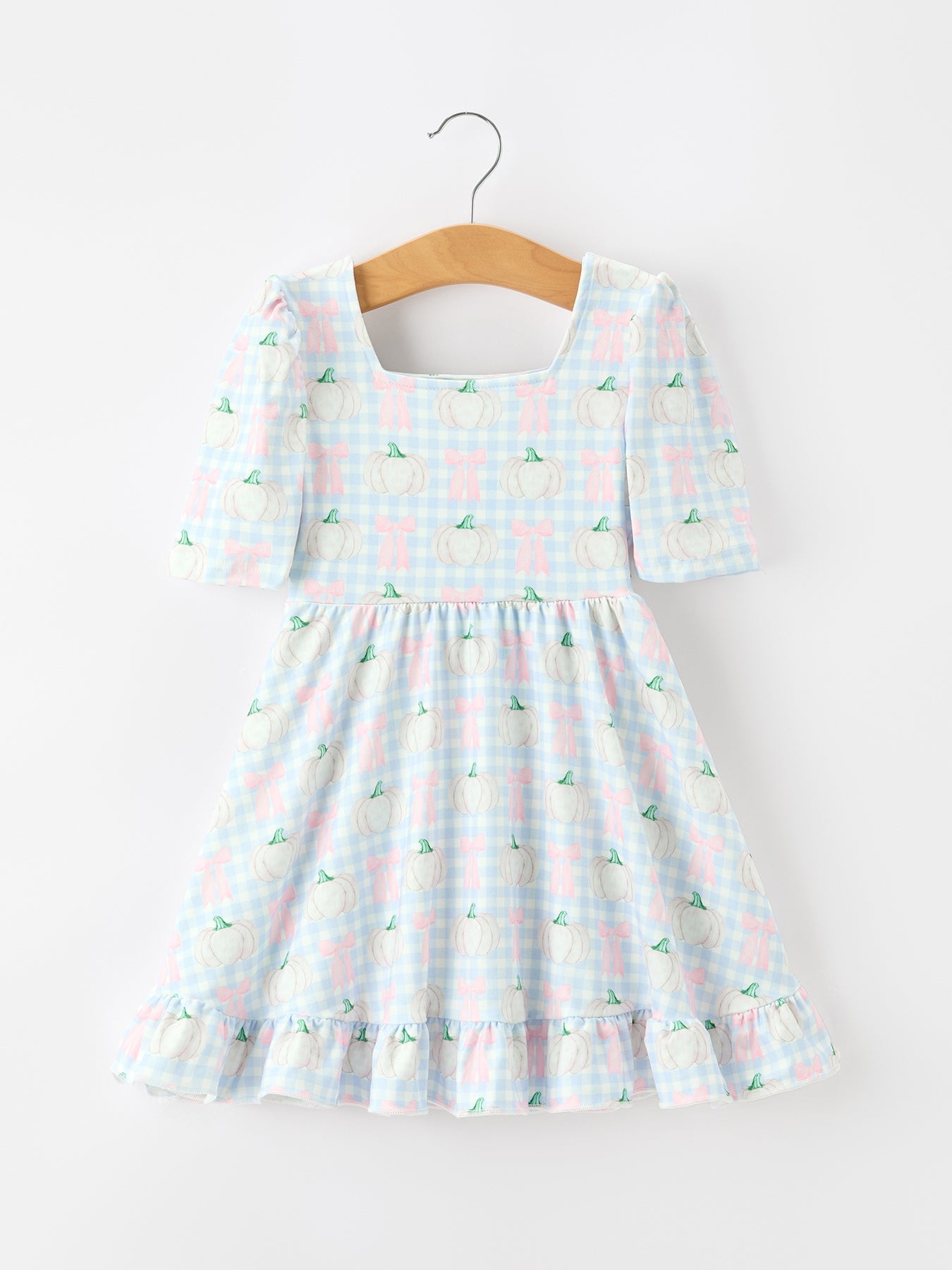 Girls dress in blue plaid with white pumpkin and pink bow print, square neckline, and ruffle hem.