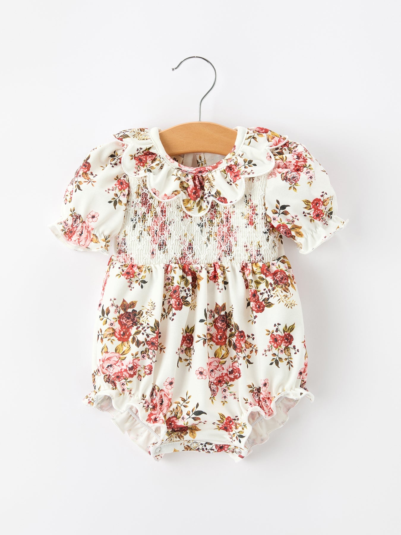Baby romper in autumn floral print with smocked bodice, ruffle petal collar, and bow accents