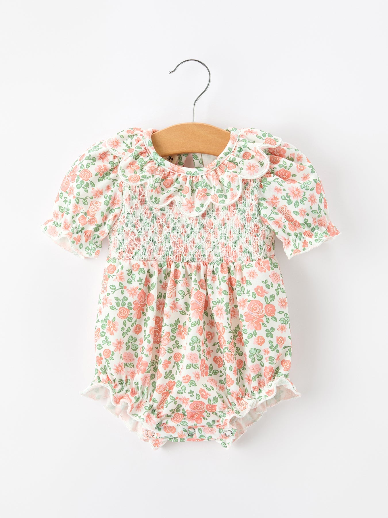 Baby romper in blush floral print with smocked front, petal collar, and puff sleeves.