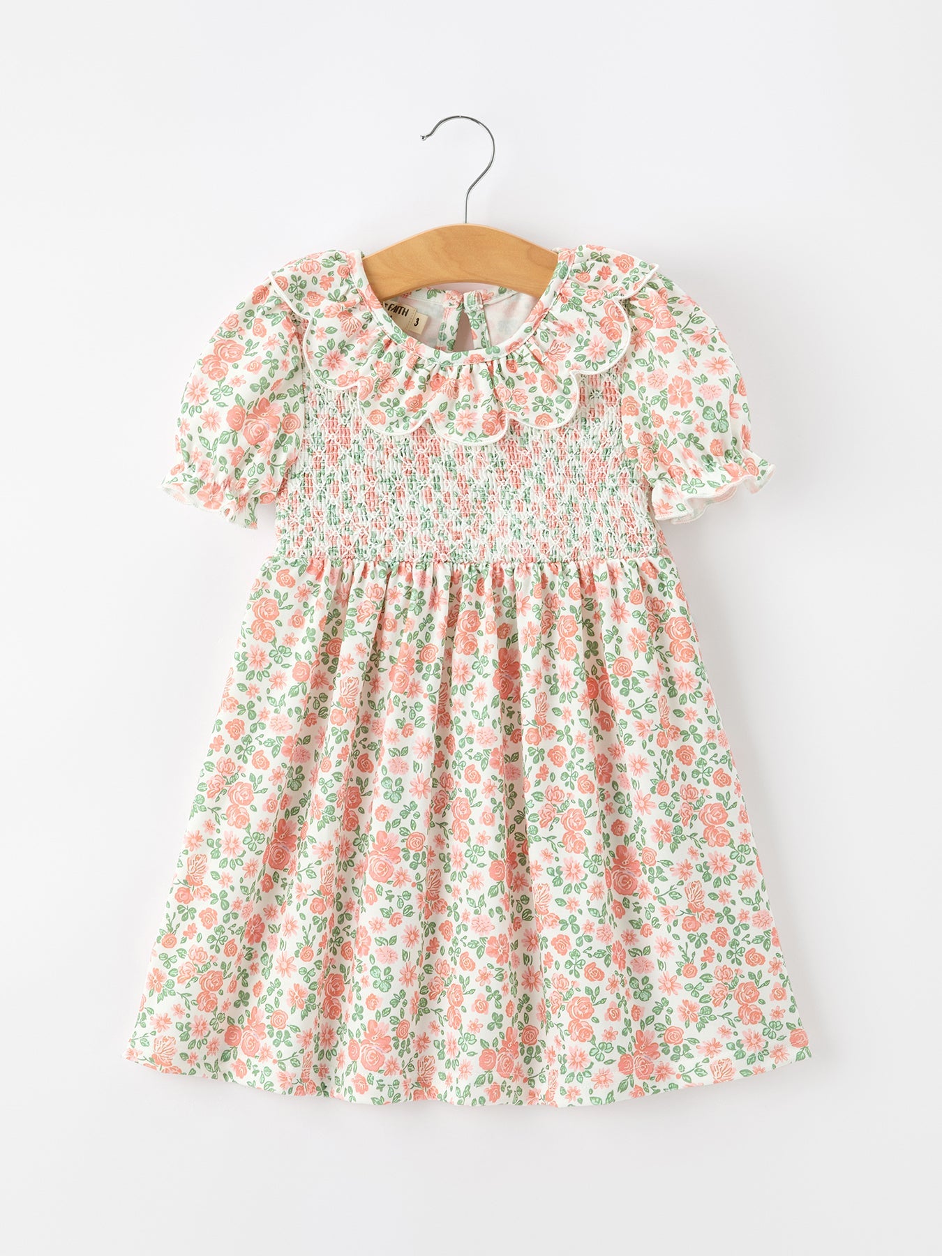 Girls dress in blush floral print with smocked bodice, petal collar, and puff sleeves.