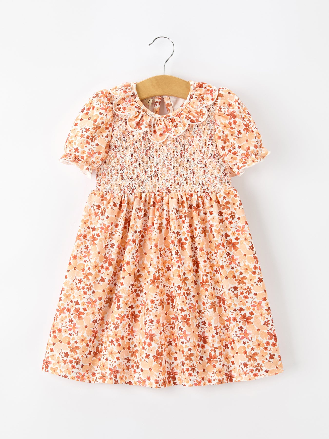 Baby girl dress in rust floral print with smocked bodice and ruffled petal collar neckline.