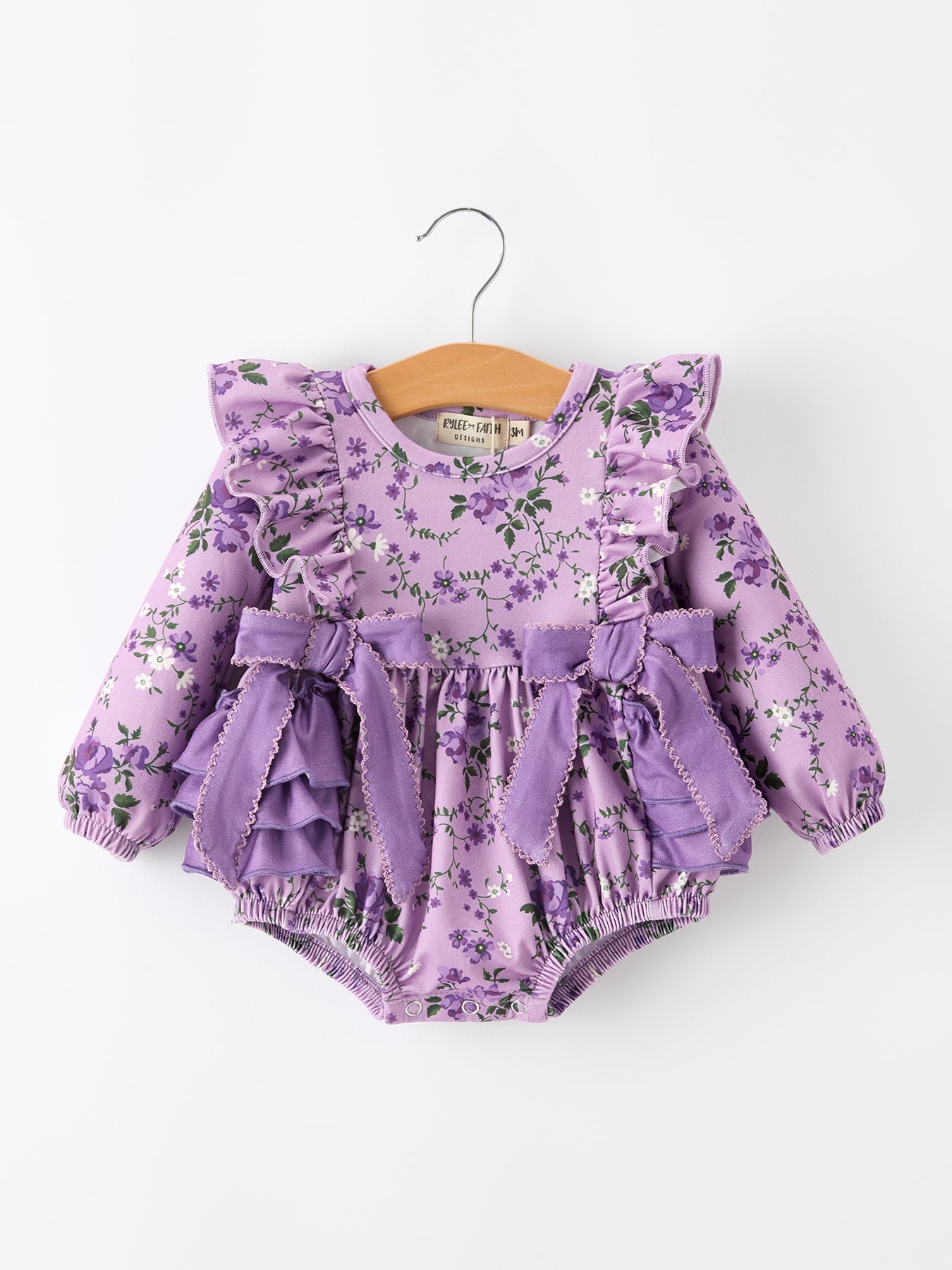 Long sleeve girls romper with a purple and green floral print and ruffle detail.