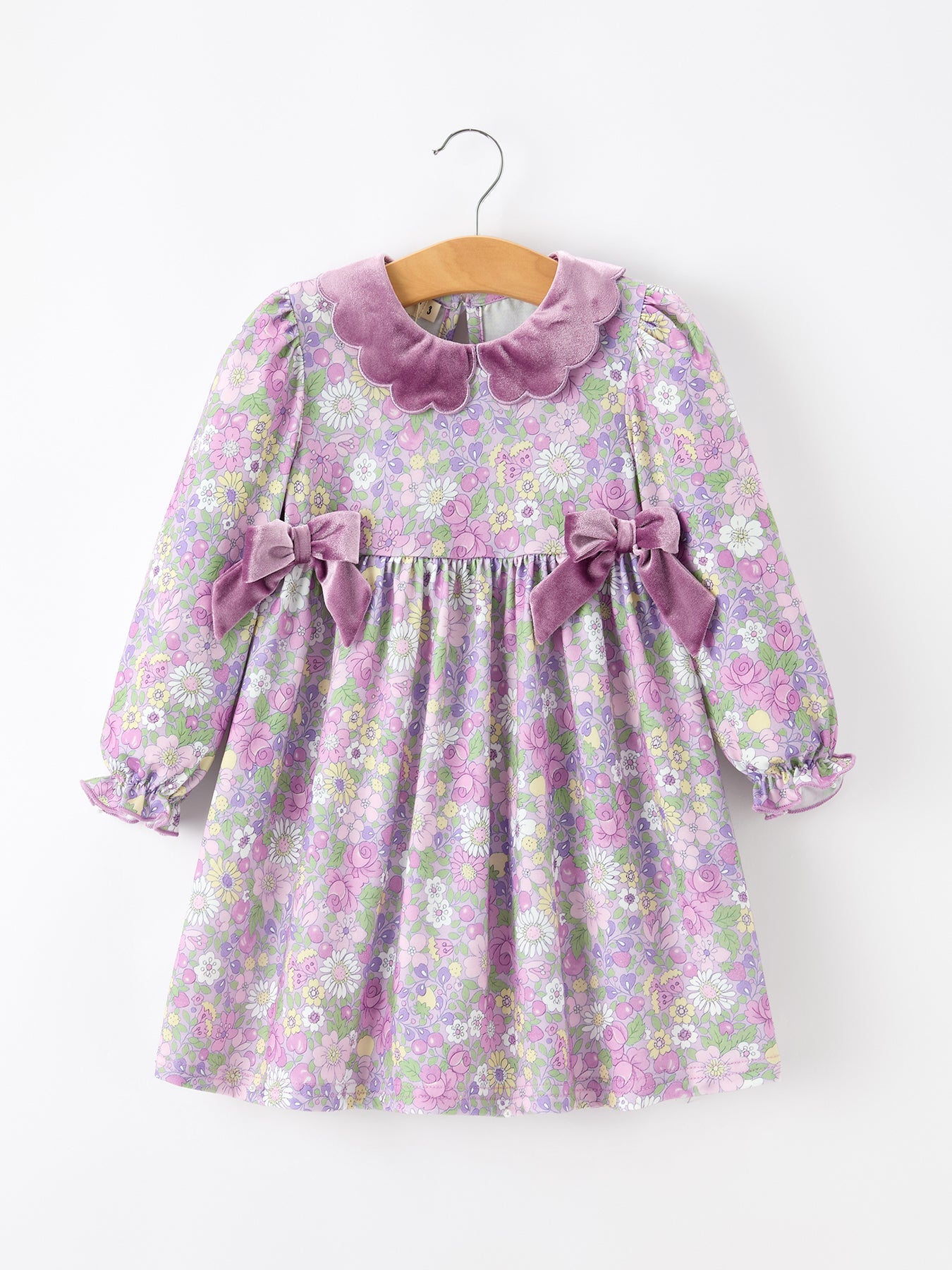Purple floral long-sleeve girls' dress with a velvet scalloped collar and decorative side bows at the waist.