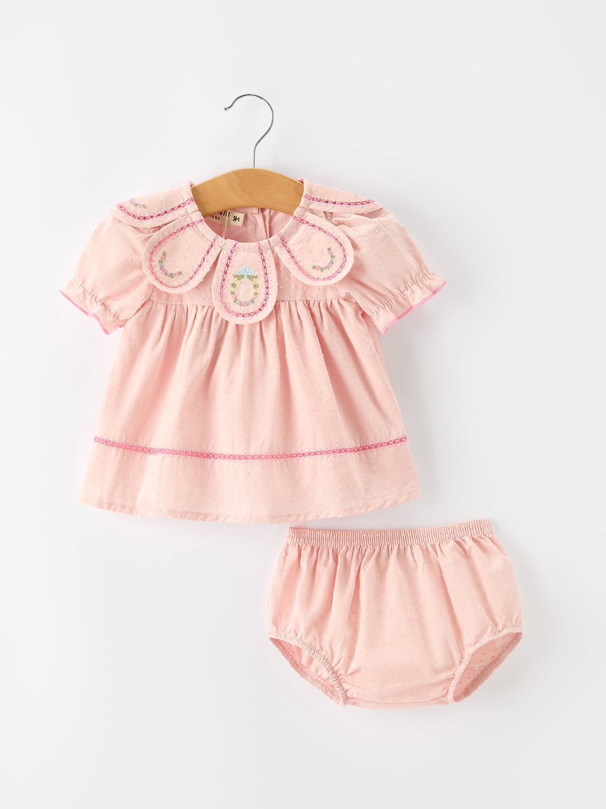 Cotton baby romper with Peter Pan collar, floral wreath embroidery, and a bow accent at the neckline