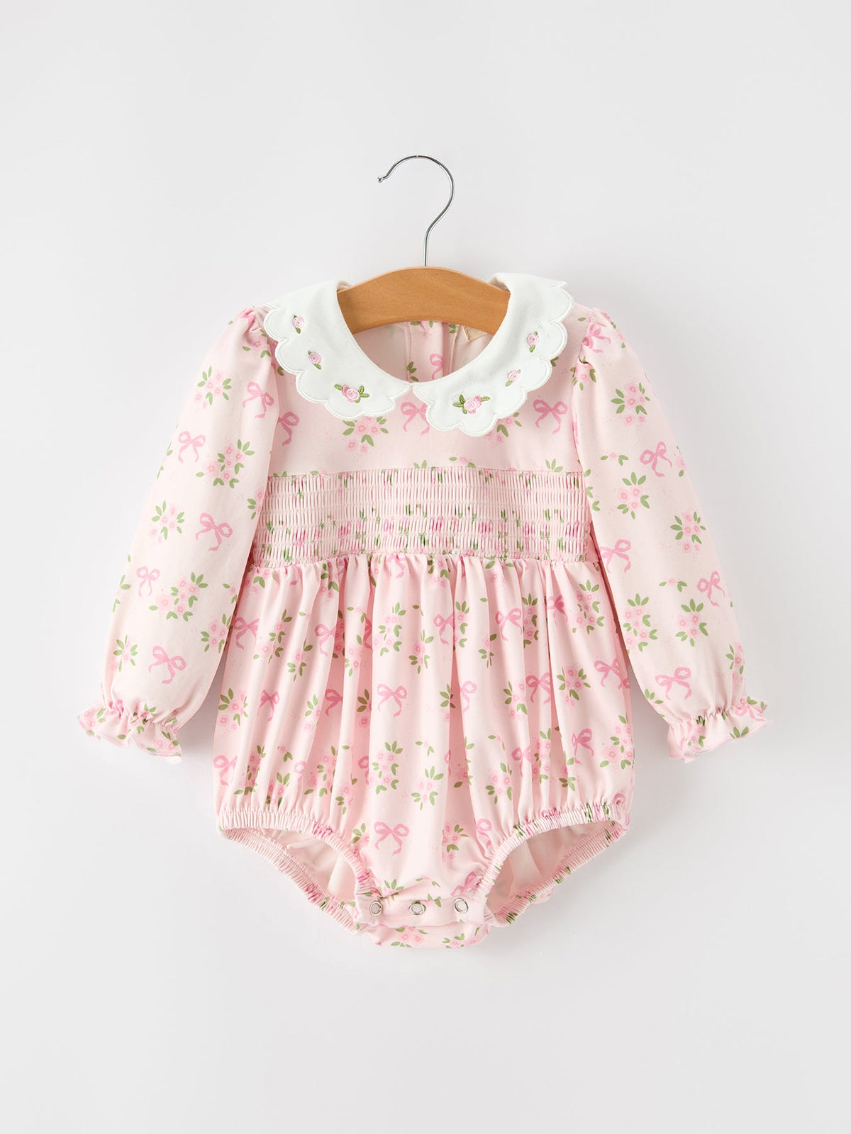 Baby girl romper in pink bow and floral print with embroidered scalloped collar, smocked chest, long sleeves and ruffle cuffs