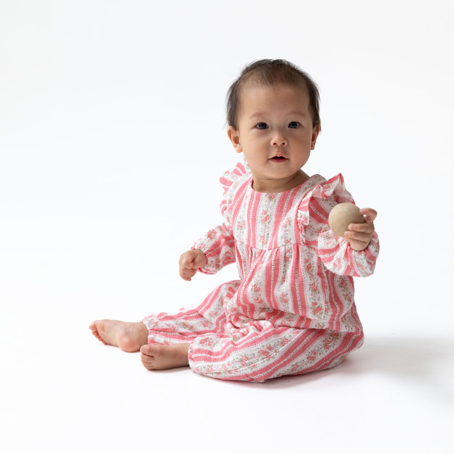 Ruffle sleeve baby romper in Suzie floral stripe print with snap closures.