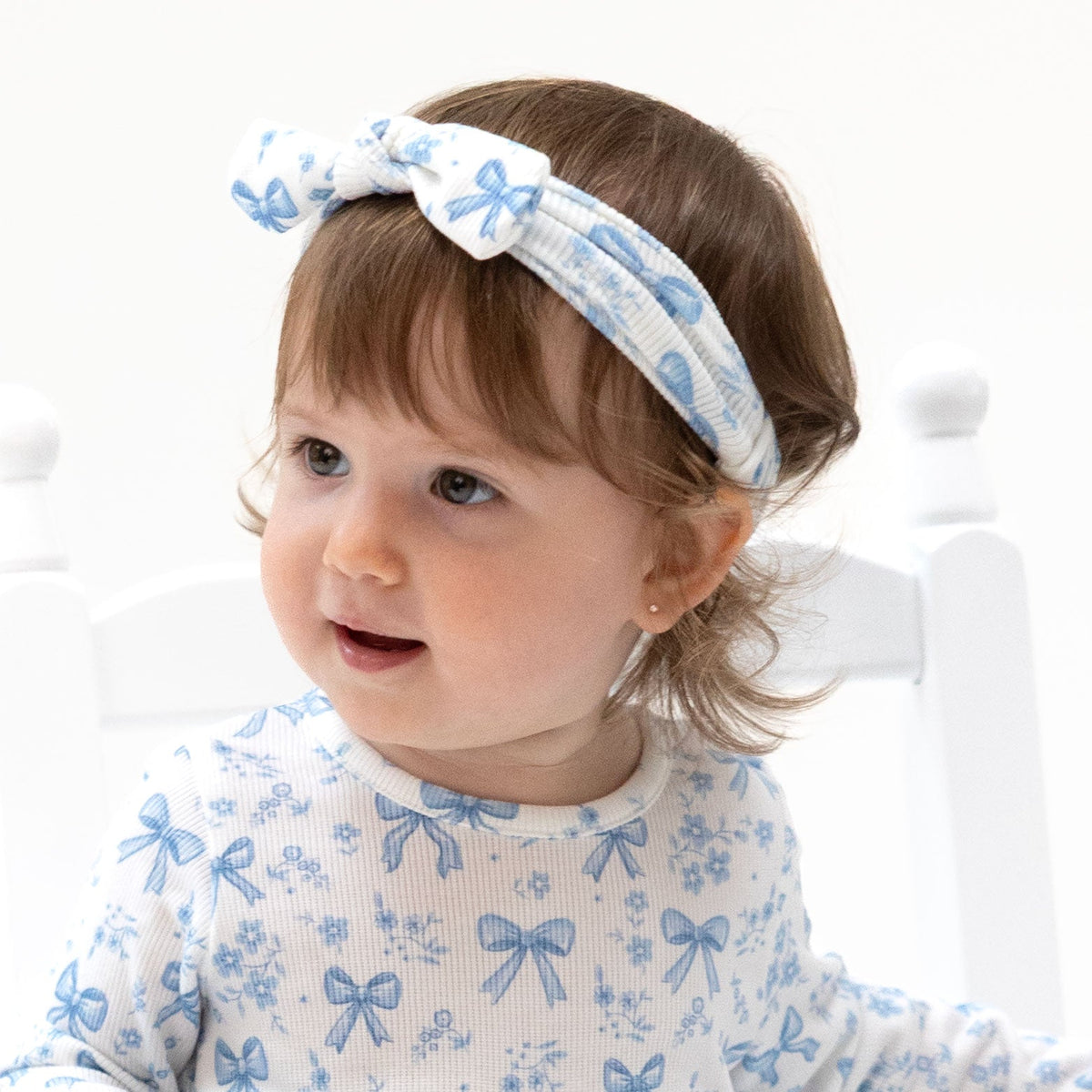 Knot headband in a blue print with small bows and flowers, tied in a classic knot detail.