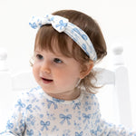 Knot headband in a blue print with small bows and flowers, tied in a classic knot detail.