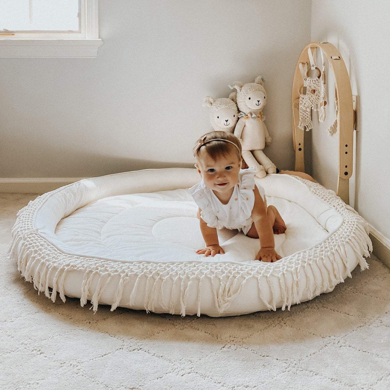 Finn + Emma organic macrame round play mat on a nursery floor, with a baby happily playing.