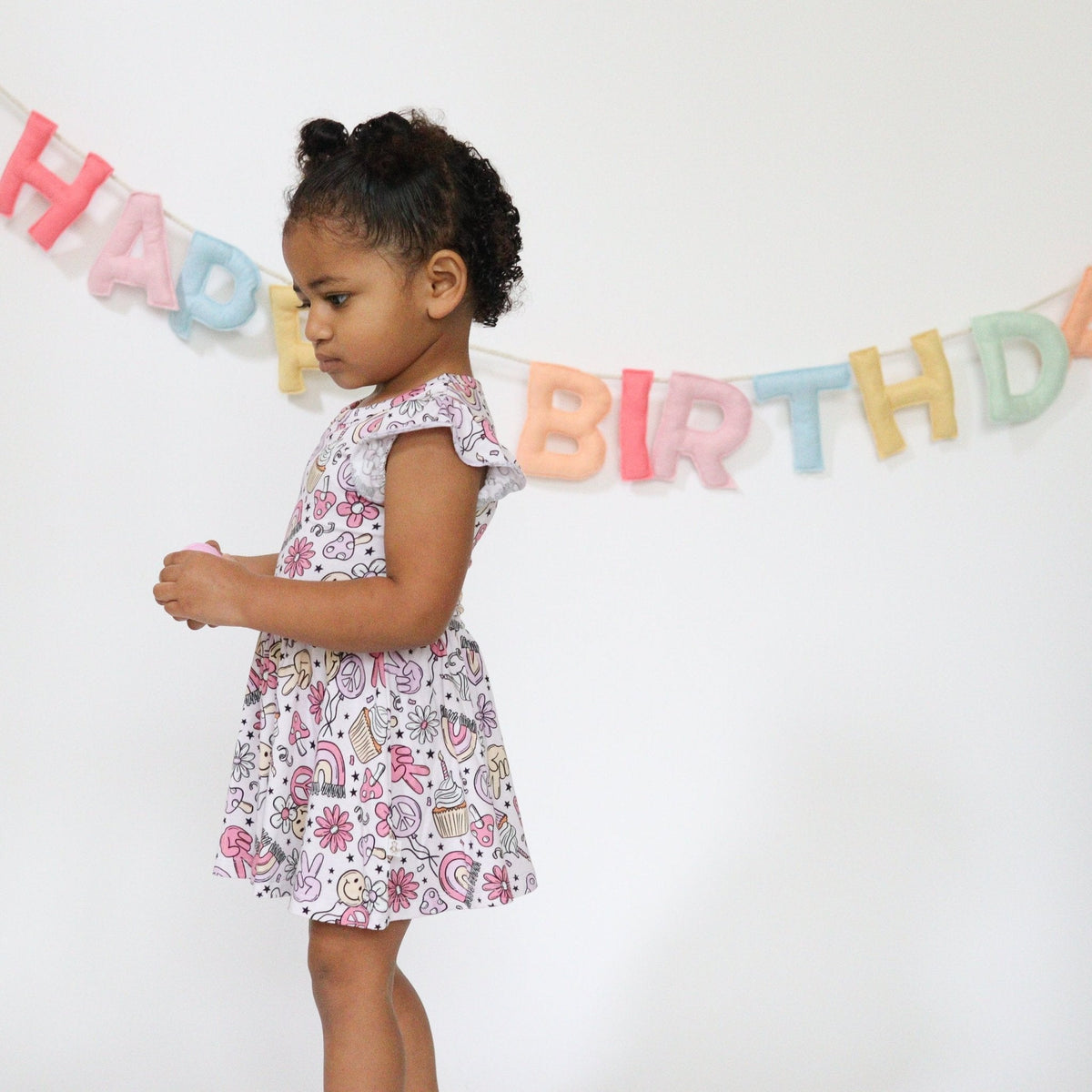 Baby bodysuit twirl dress with a groovy birthday print, twirl skirt, and snap closures at the bottom.