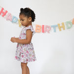 Baby bodysuit twirl dress with a groovy birthday print, twirl skirt, and snap closures at the bottom.