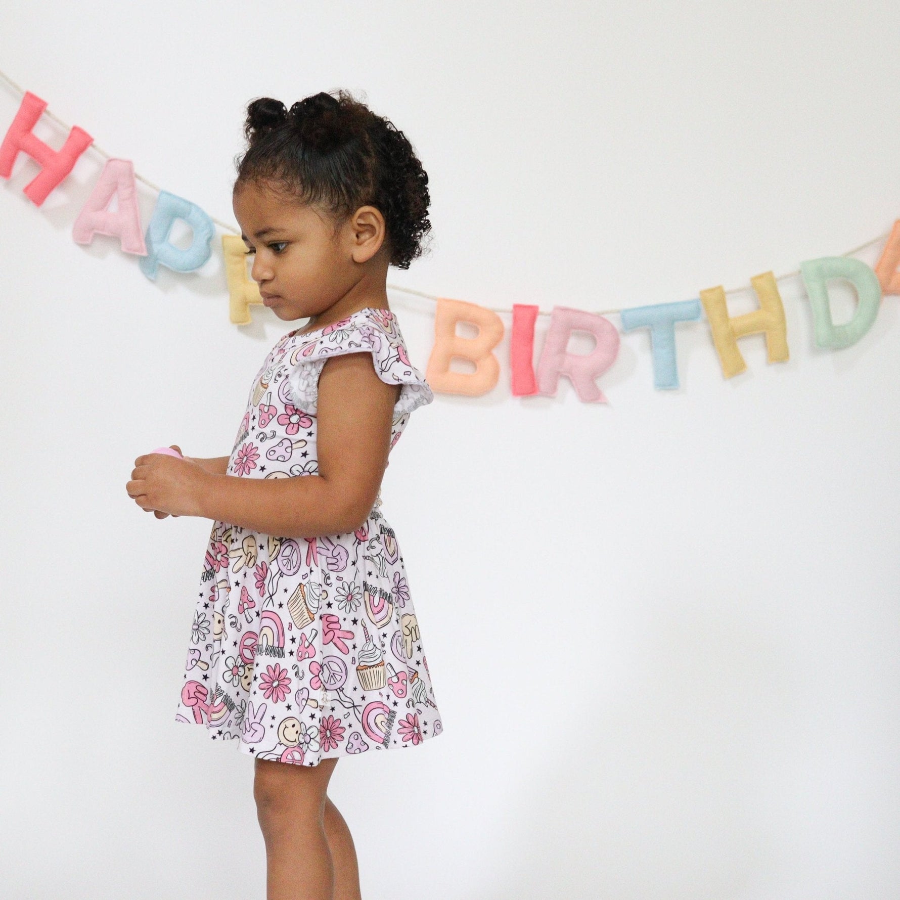 Baby bodysuit twirl dress with a groovy birthday print, twirl skirt, and snap closures at the bottom.