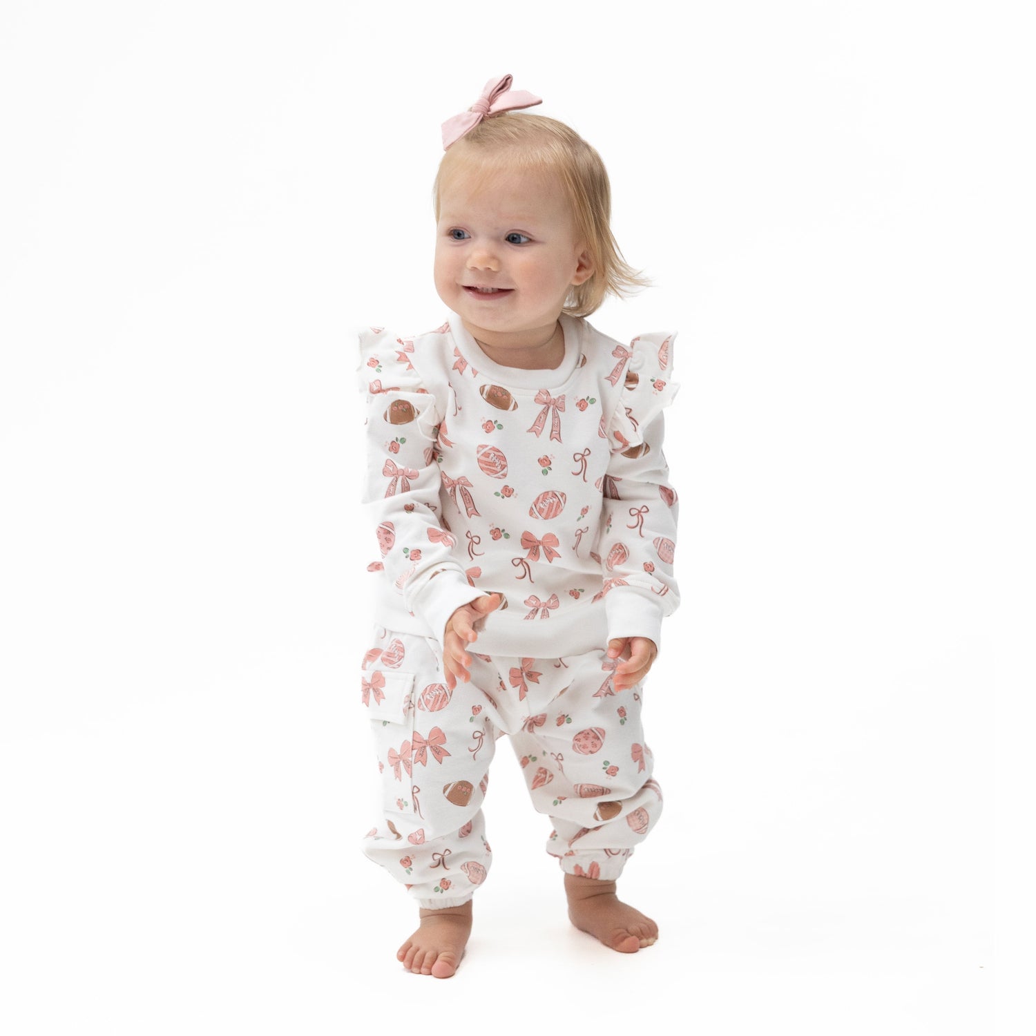 Two-piece set with a shoulder-ruffle sweatshirt and cargo pants in a footballs and bows print.