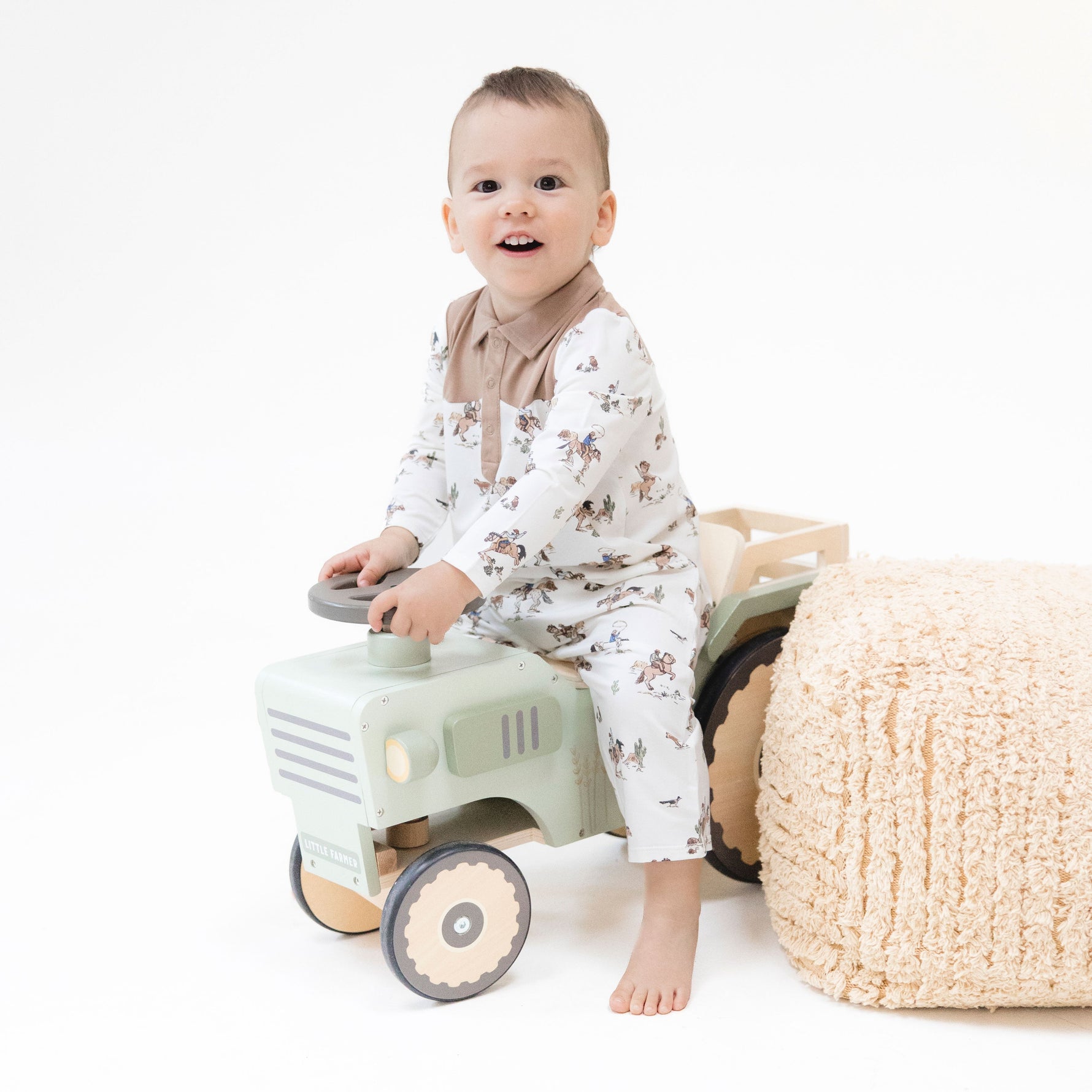 Long sleeve baby romper in a scattered horse print, laid flat with snap closures along the front