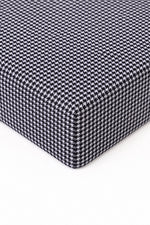 Crib sheet in black and white houndstooth print fitted over a standard crib mattress