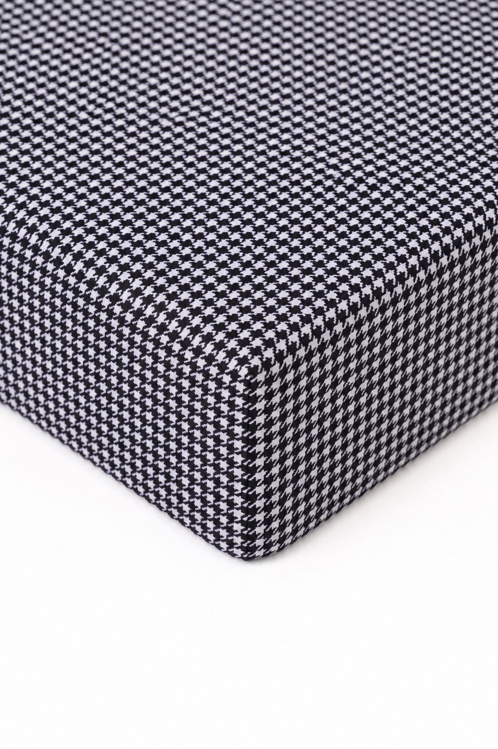 Crib sheet in black and white houndstooth print fitted over a standard crib mattress