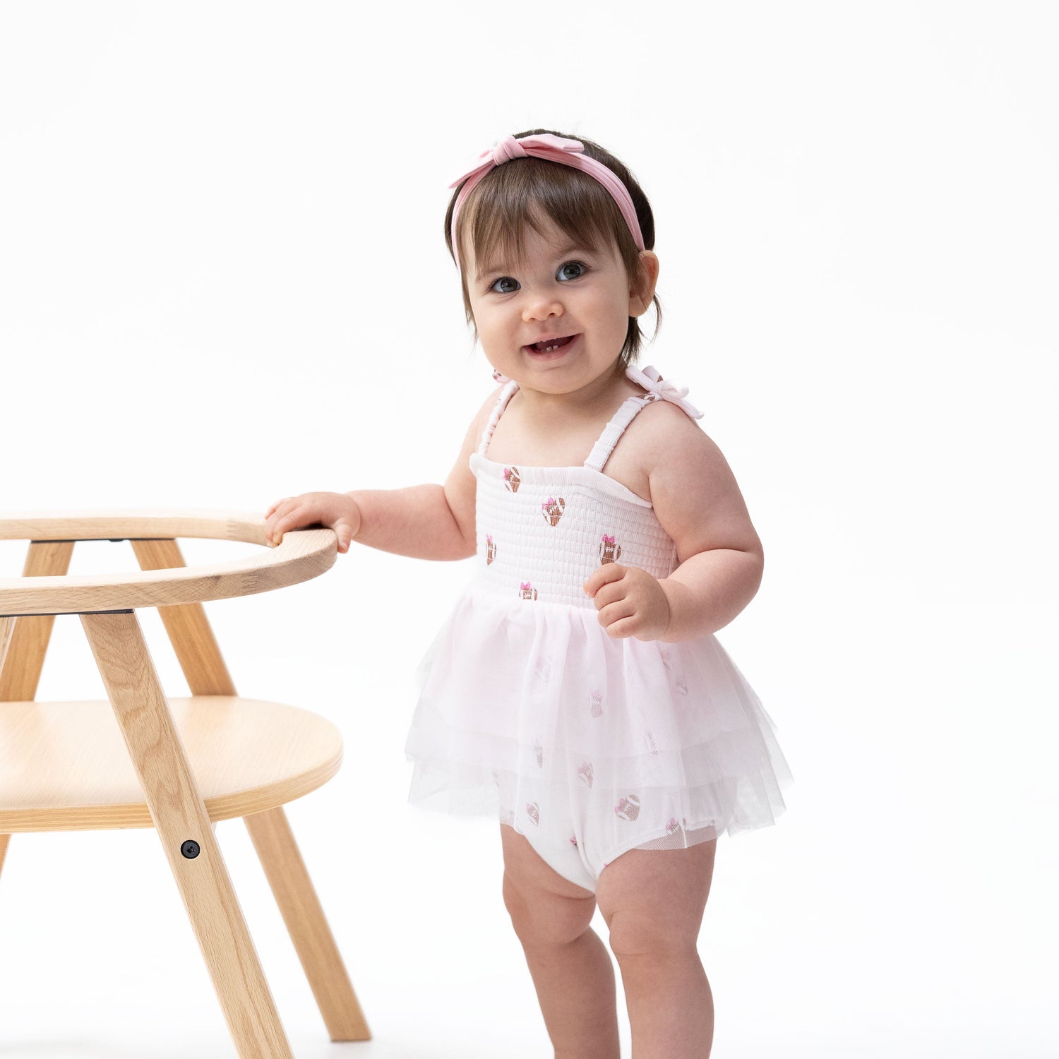 Bubble romper with a tulle tutu skirt and ruffle trim in a mini football hearts print.