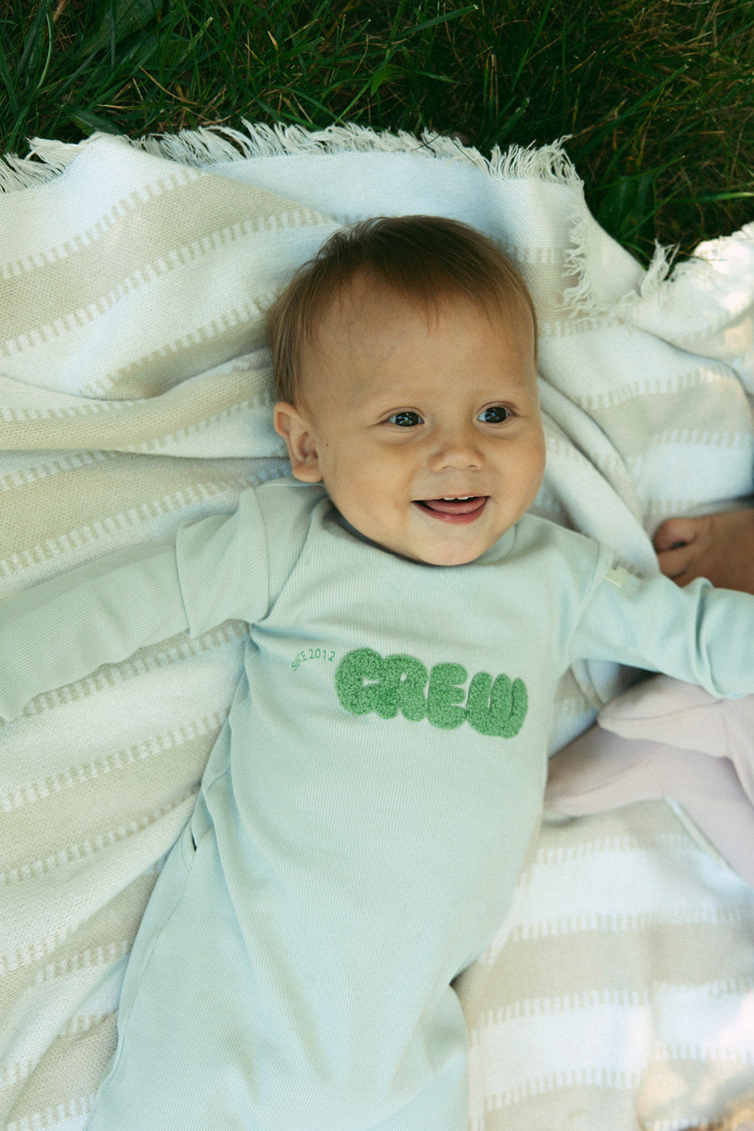 Crew Kids NY athletic footie green long sleeve baby onesie with cuff sleeves, snap closure.