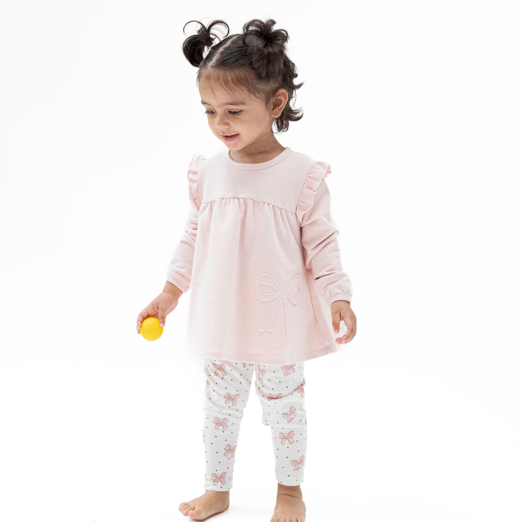 Two-piece set with pink long sleeve ruffle-shoulder tunic featuring a bow applique and matching ribbed leggings