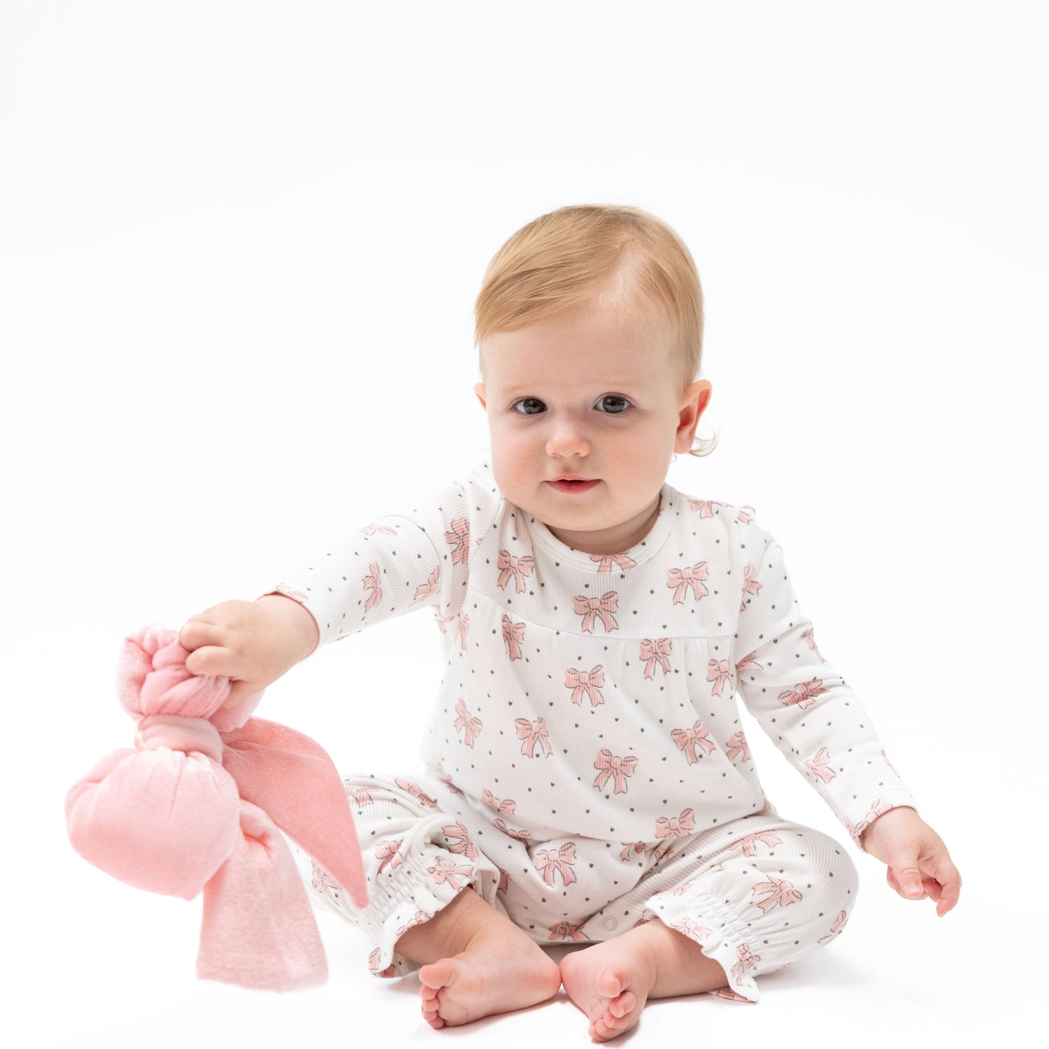 Baby romper in a bows and hearts print with cuffed sleeves and legs and snap closures
