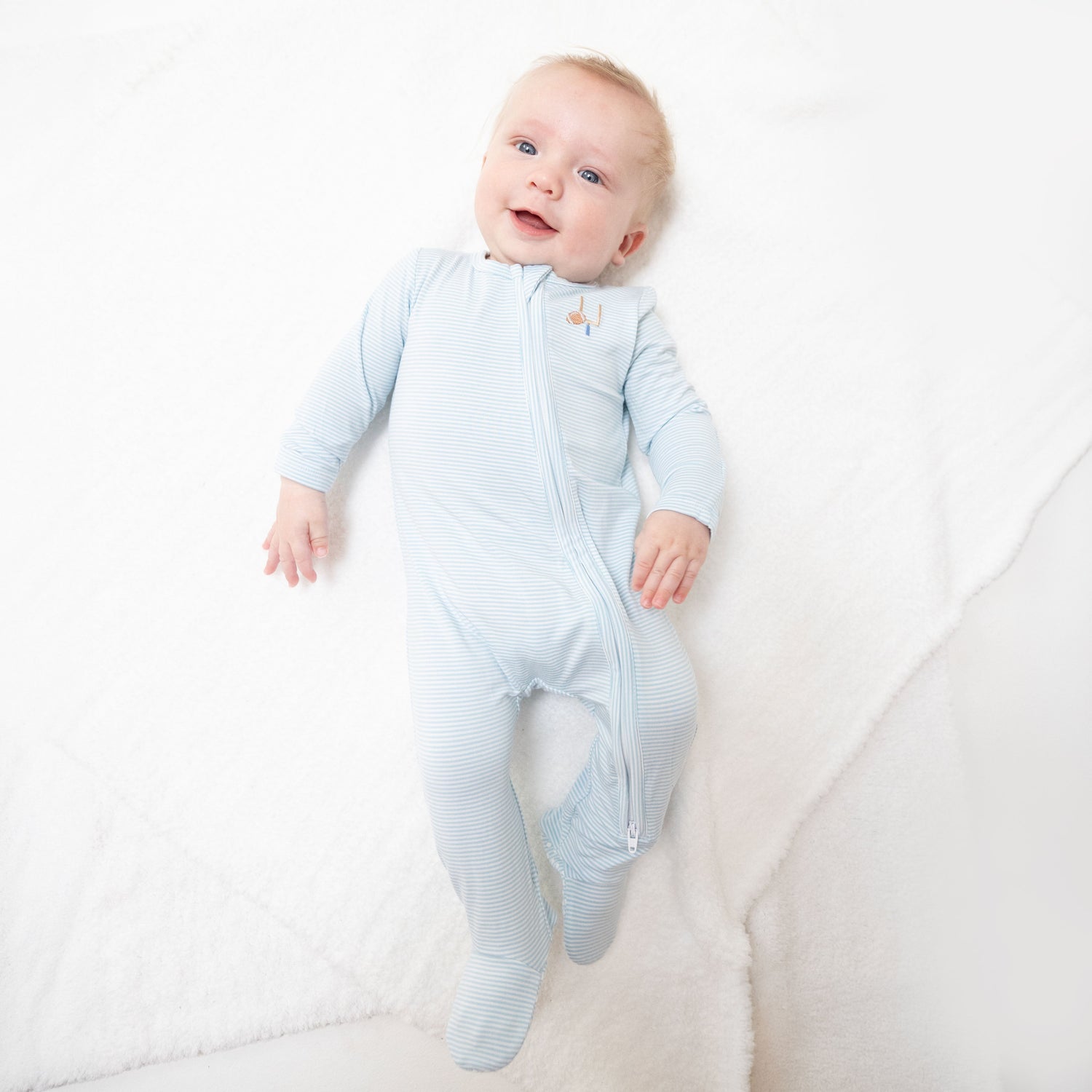 Baby footie pajamas in blue micro stripe with a small football print, two-way zipper and footed legs.