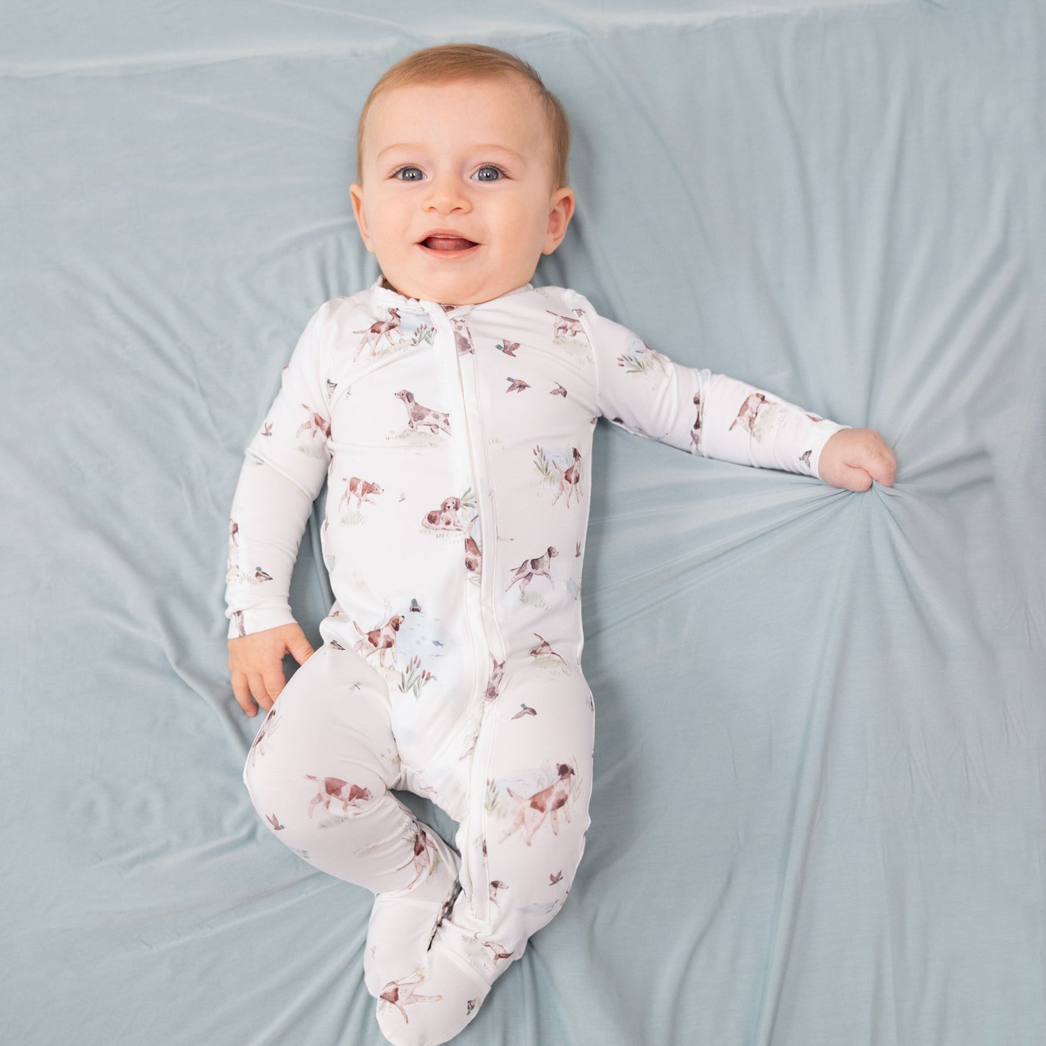 Baby footie pajamas with pointer dog and duck print, two-way zipper down the front, and footed grippers.
