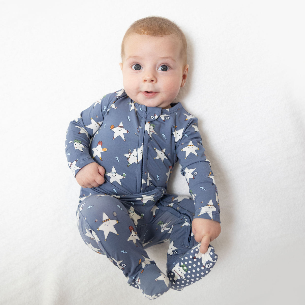 Baby footie pajamas in a sports all-stars print that glows in the dark, with a two-way front zipper and footed legs.