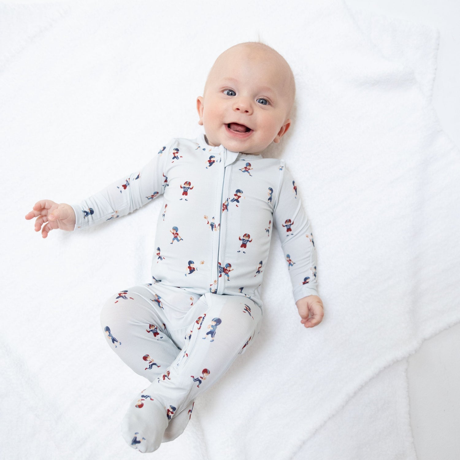 Footie pajamas in a tiny footballers print with a full-length two-way zipper and gripper feet.