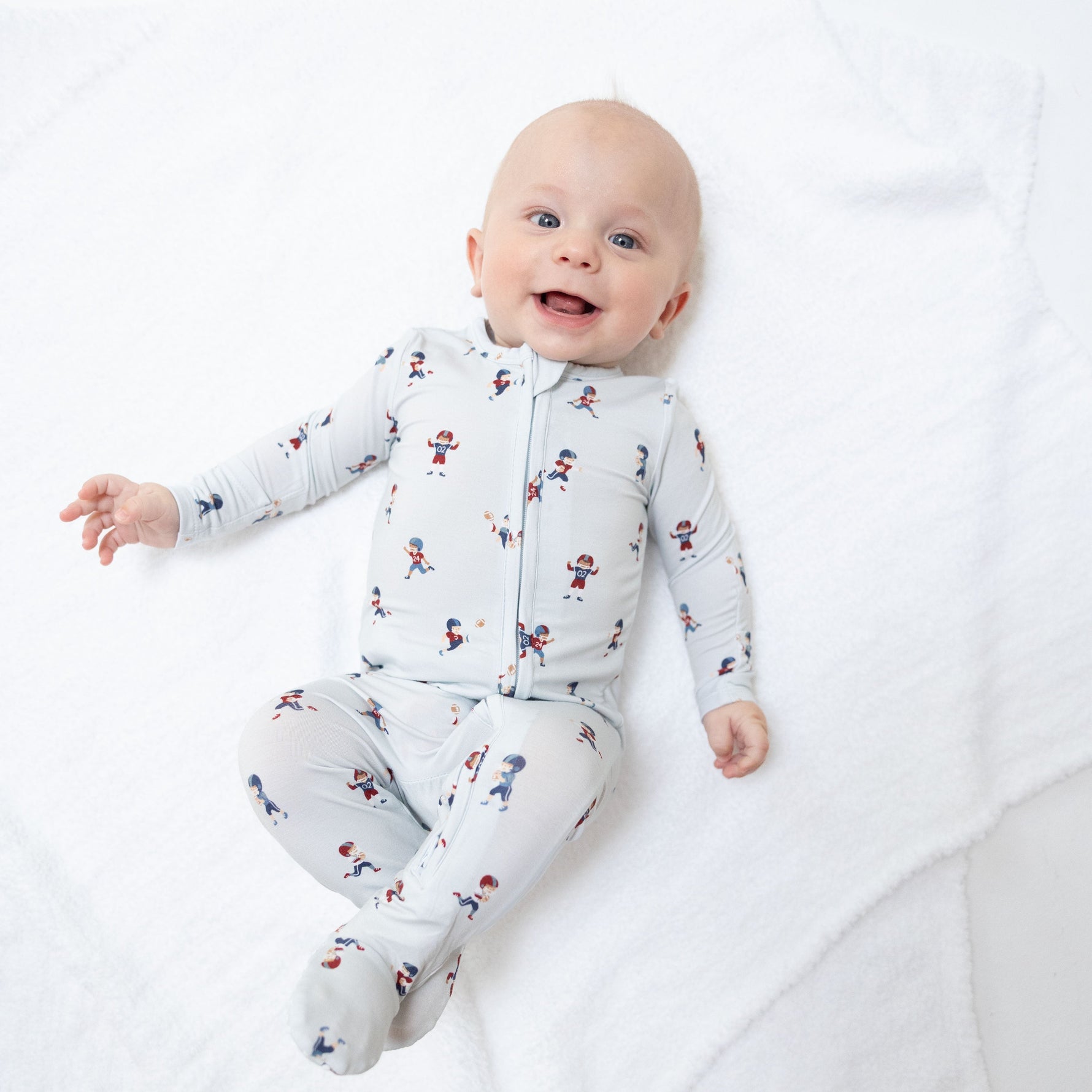 Footie pajamas in a tiny footballers print with a full-length two-way zipper and gripper feet.