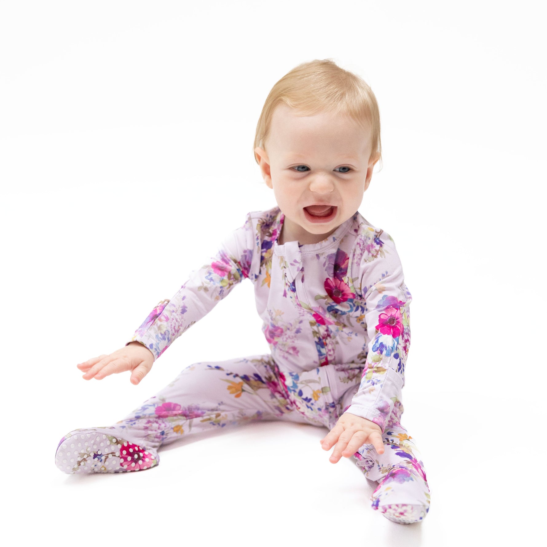 Footie pajamas in a dahlia floral print with a ruffle back detail and full-length two-way zipper.