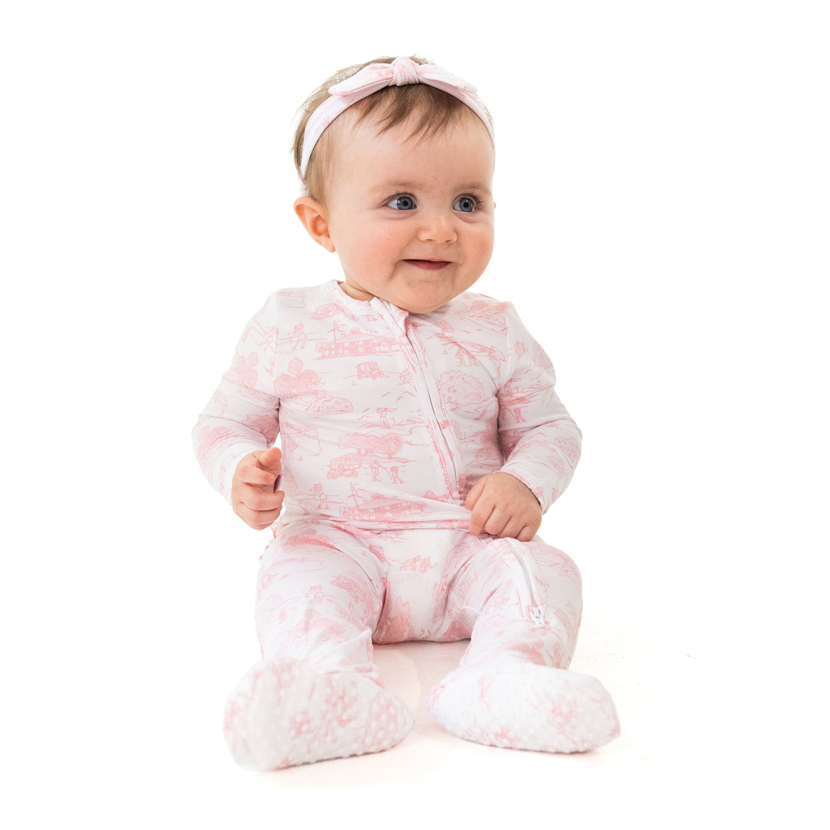 Ruffle back zipper footie in pink golf toile print with fold-over cuffs and non-slip foot grippers.