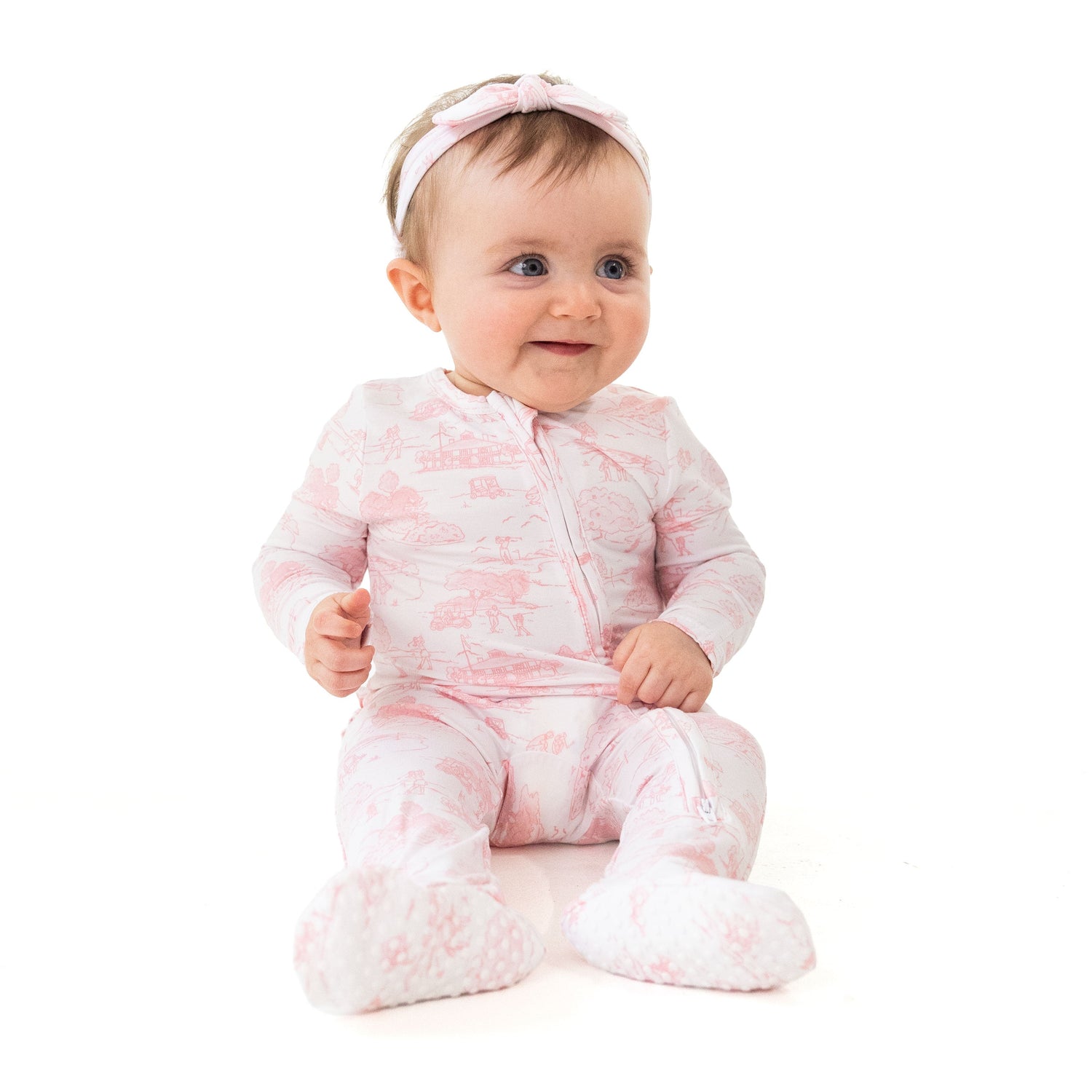 Ruffle back zipper footie in pink golf toile print with fold-over cuffs and non-slip foot grippers.
