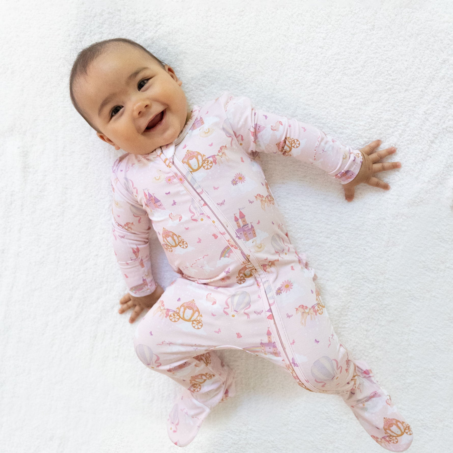 Footie pajamas with a princess unicorns and castle print, ruffle back detail, and front zipper
