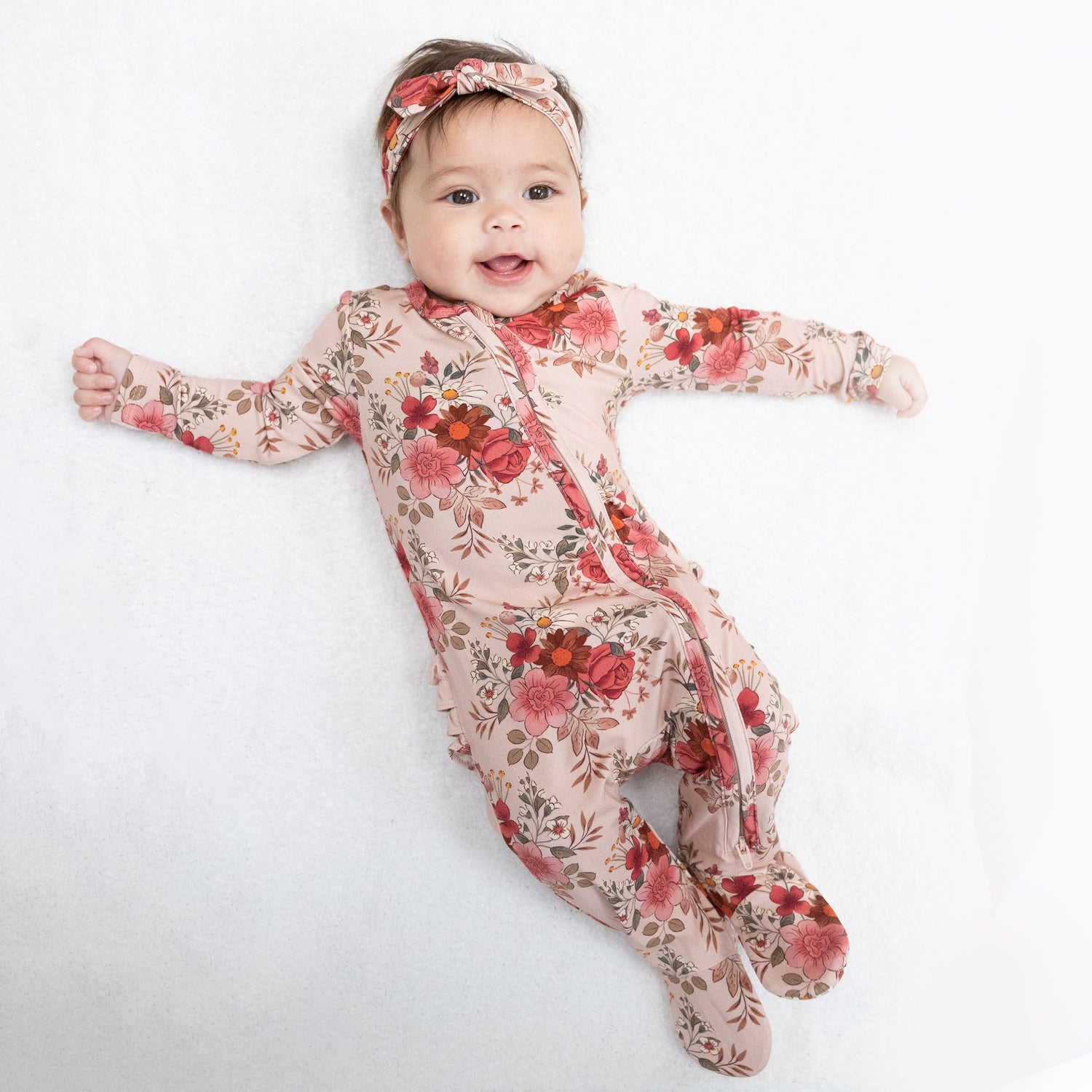 Zippered baby footie in Sabrina floral print with a ruffle back detail and fold-over cuffs