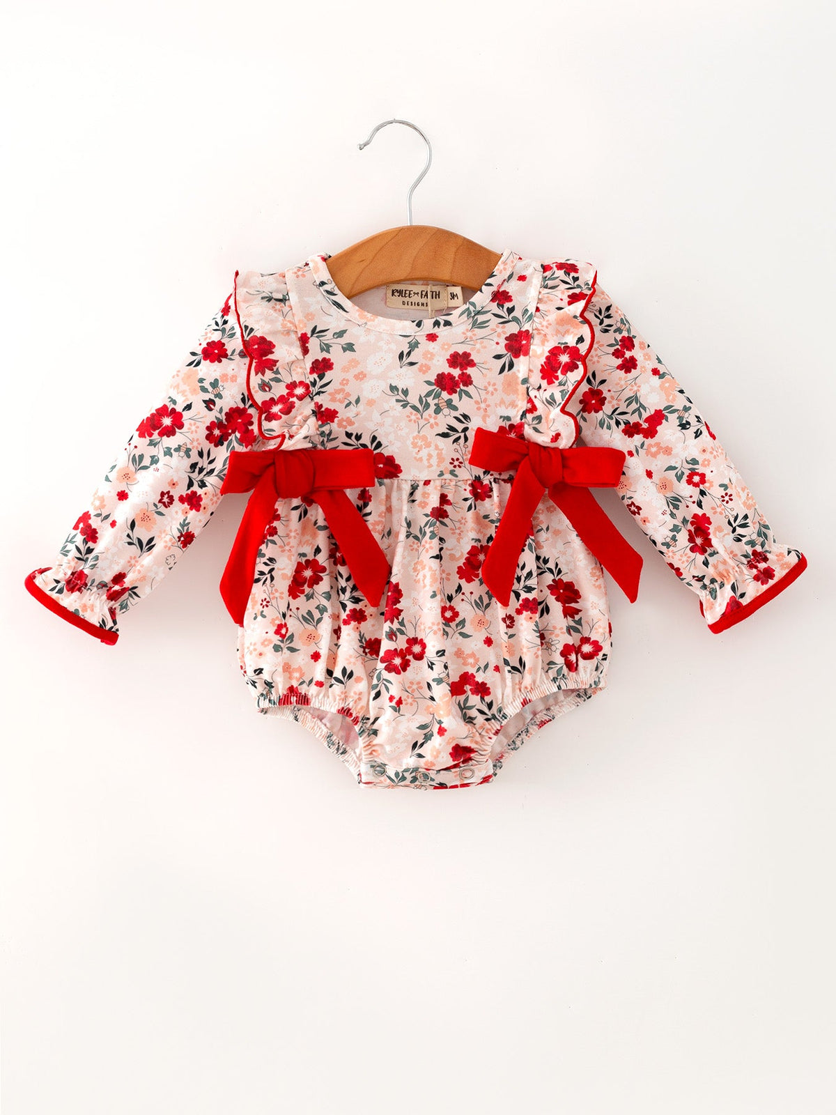 Long-sleeve baby girl romper with fall floral print, ruffle details, and decorative bows