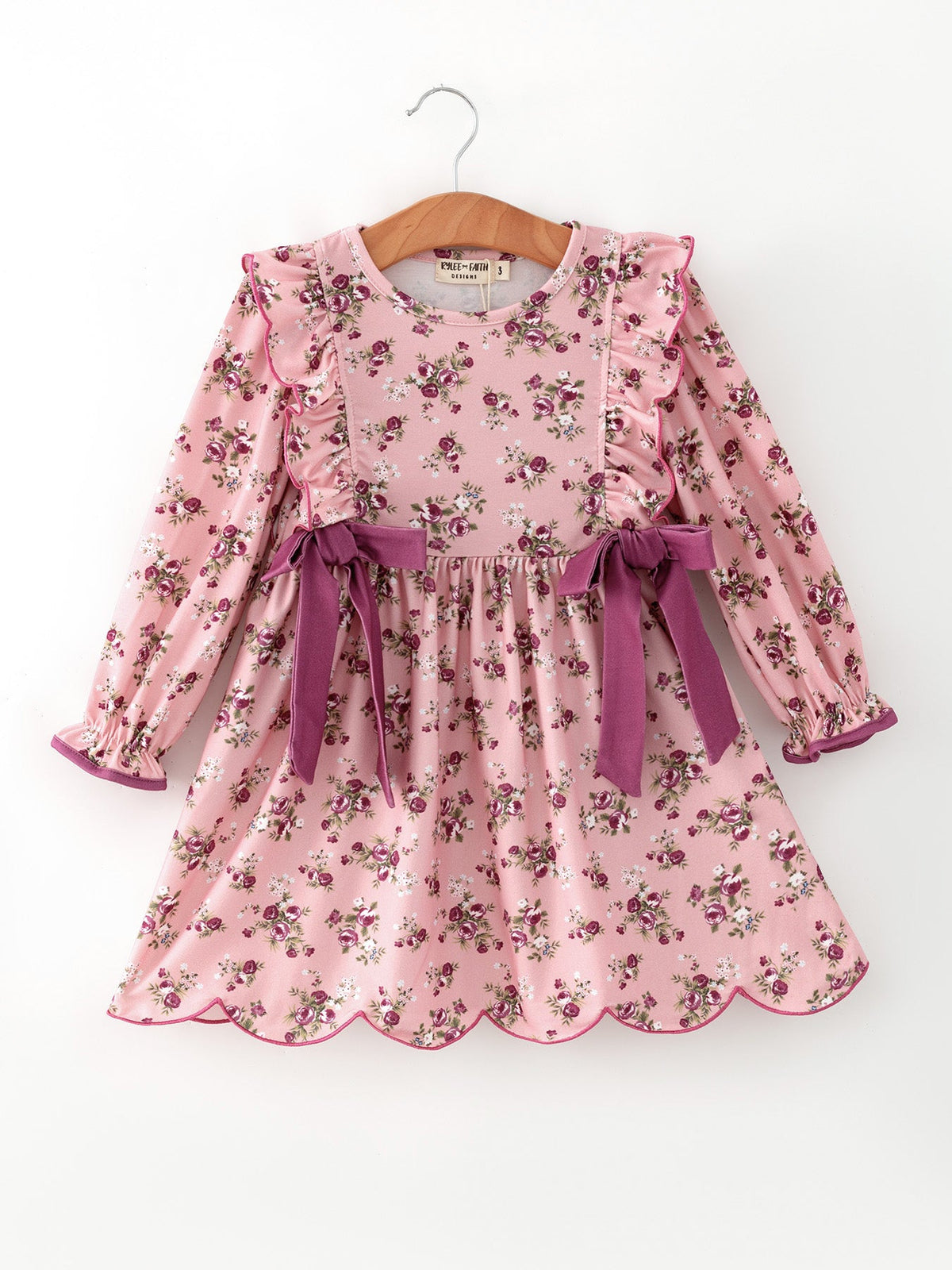 Long sleeve girls dress with rose floral print, ruffles, waist bow, and scalloped hem