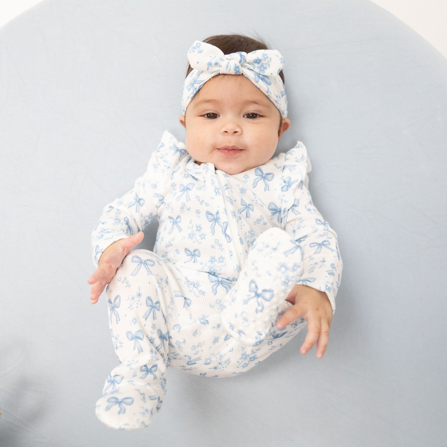 Ruffle-sleeve zipper footie in a blue bows and flowers print with fold-over cuffs and footed grippers.