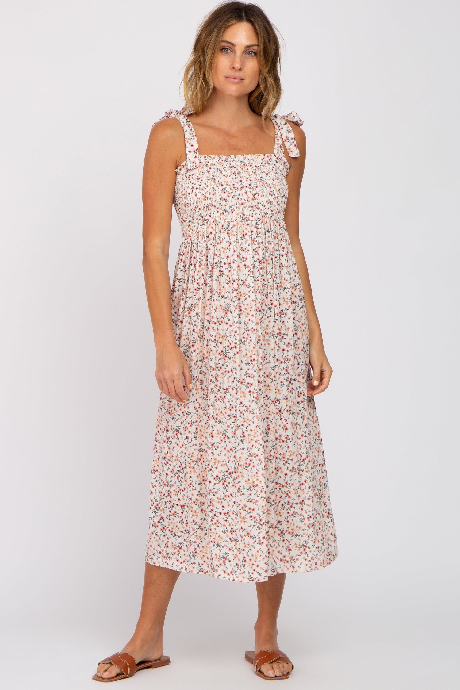 Cream floral midi dress with smocked top, square neckline, and self-tie straps, shown with sandals.