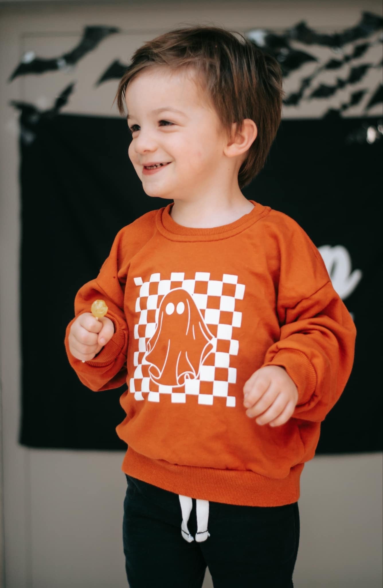 Orange crewneck sweatshirt with a retro checkered ghost graphic on the front, oversized fit