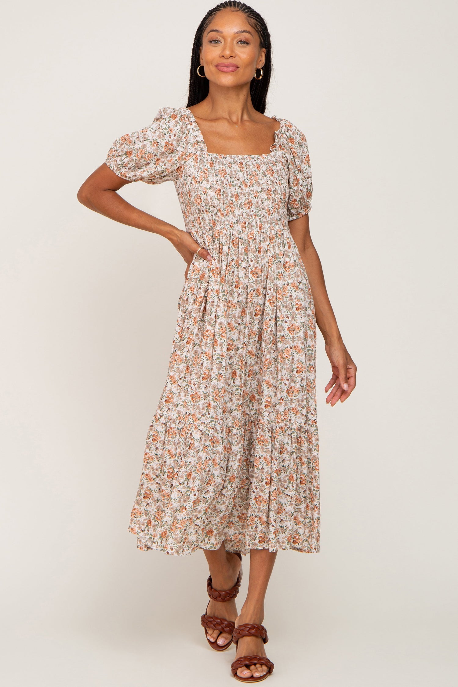 Taupe floral midi dress with a smocked bodice, puff sleeves, and a flowing skirt, styled with heeled sandals.