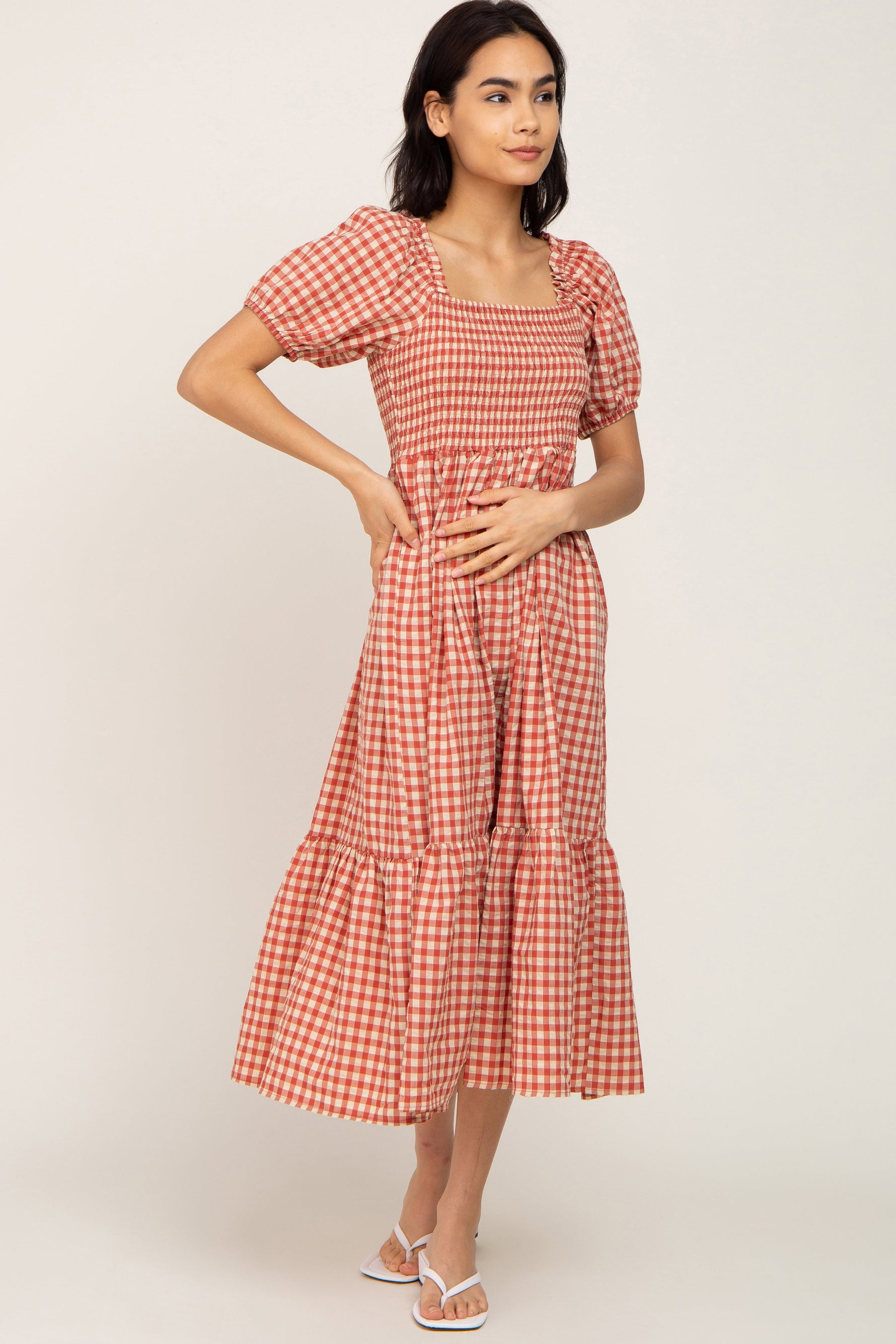 Rust gingham smocked midi dress with puff sleeves and a ruffle hem, styled with sandals.
