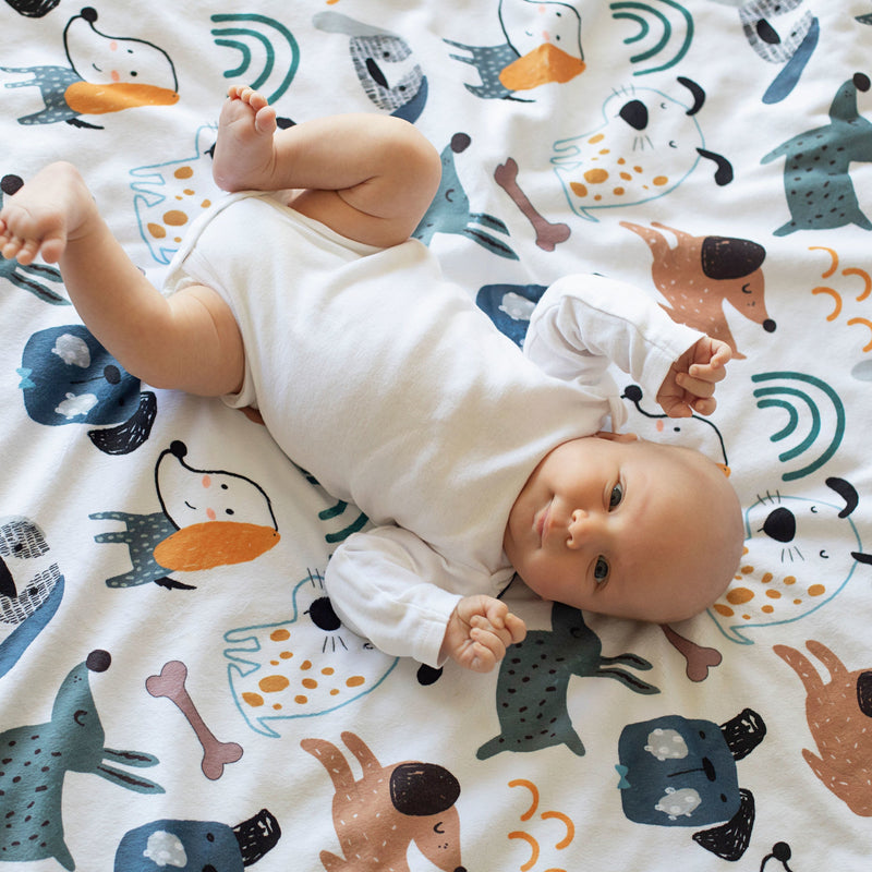 Baby lying on a dog-themed Minky blanket, showcasing soft texture and playful print.