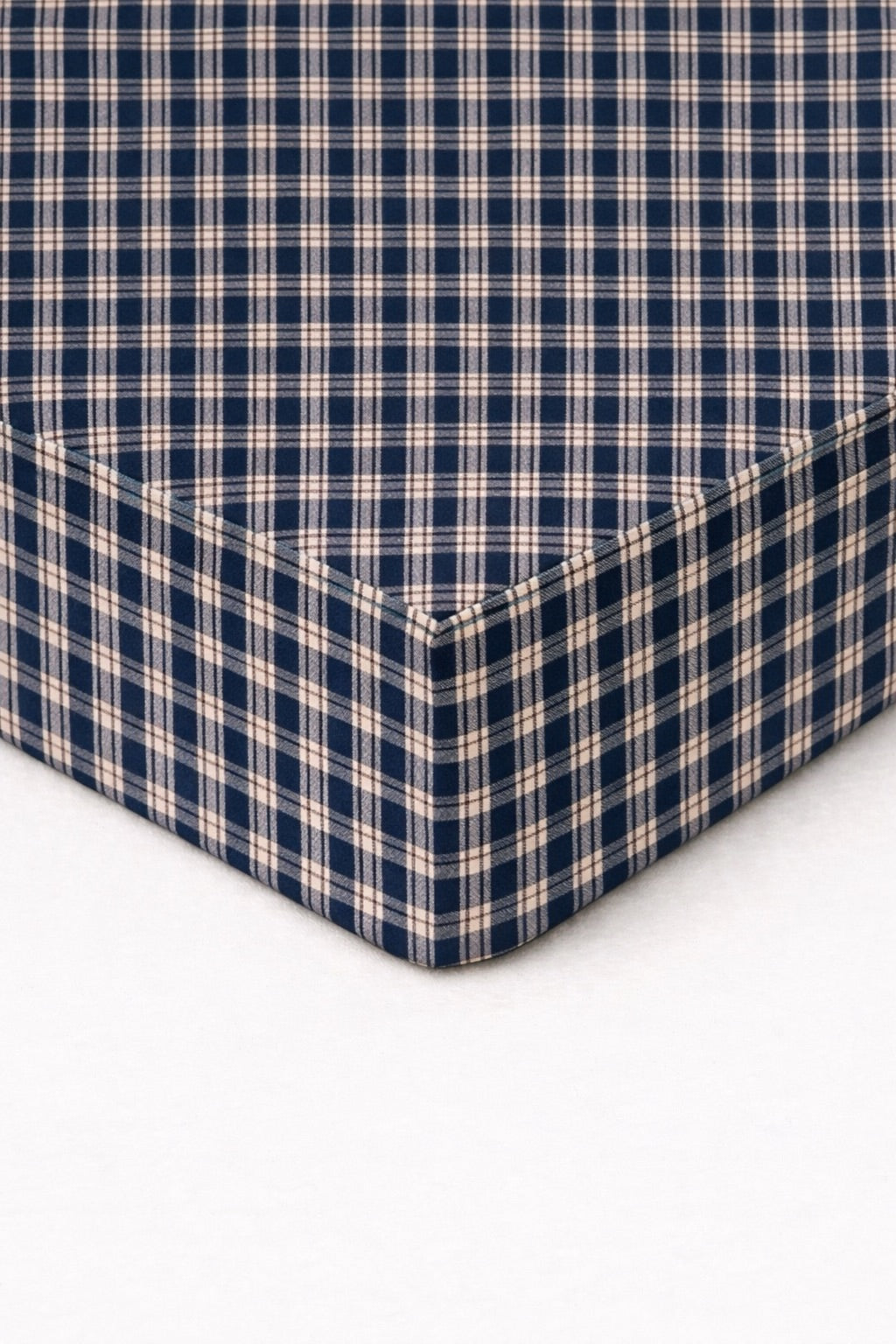 Blue and white gingham plaid crib sheet fitted over a standard crib mattress